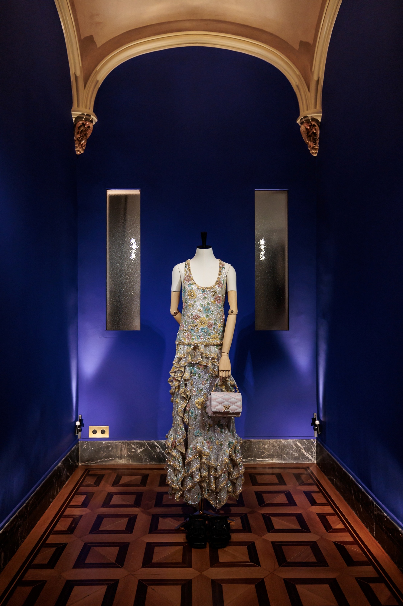 Vitrina expositora con iluminación azul en el espacio del evento Louis Vuitton Cruise 2025 en Barcelona