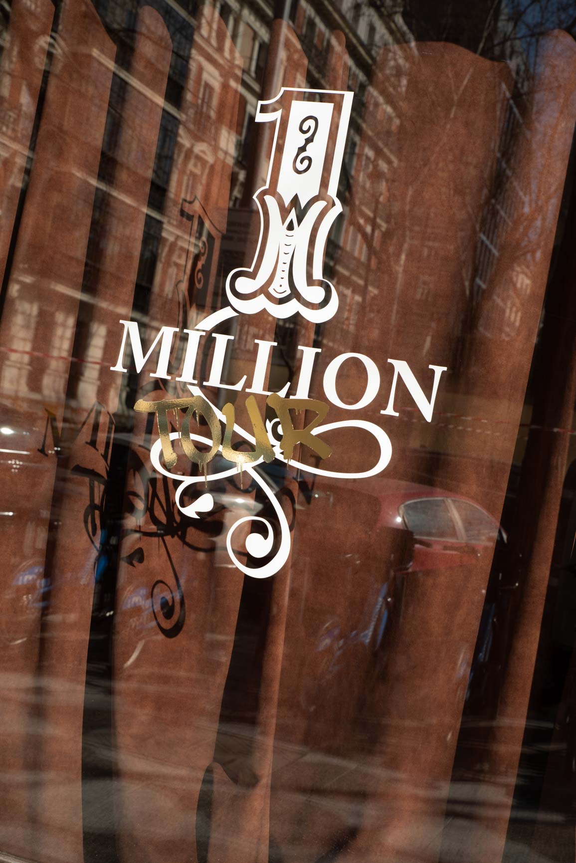 One Million logo on glass surface with reflection of Madrid architecture, exterior branding of the Rabanne pop-up