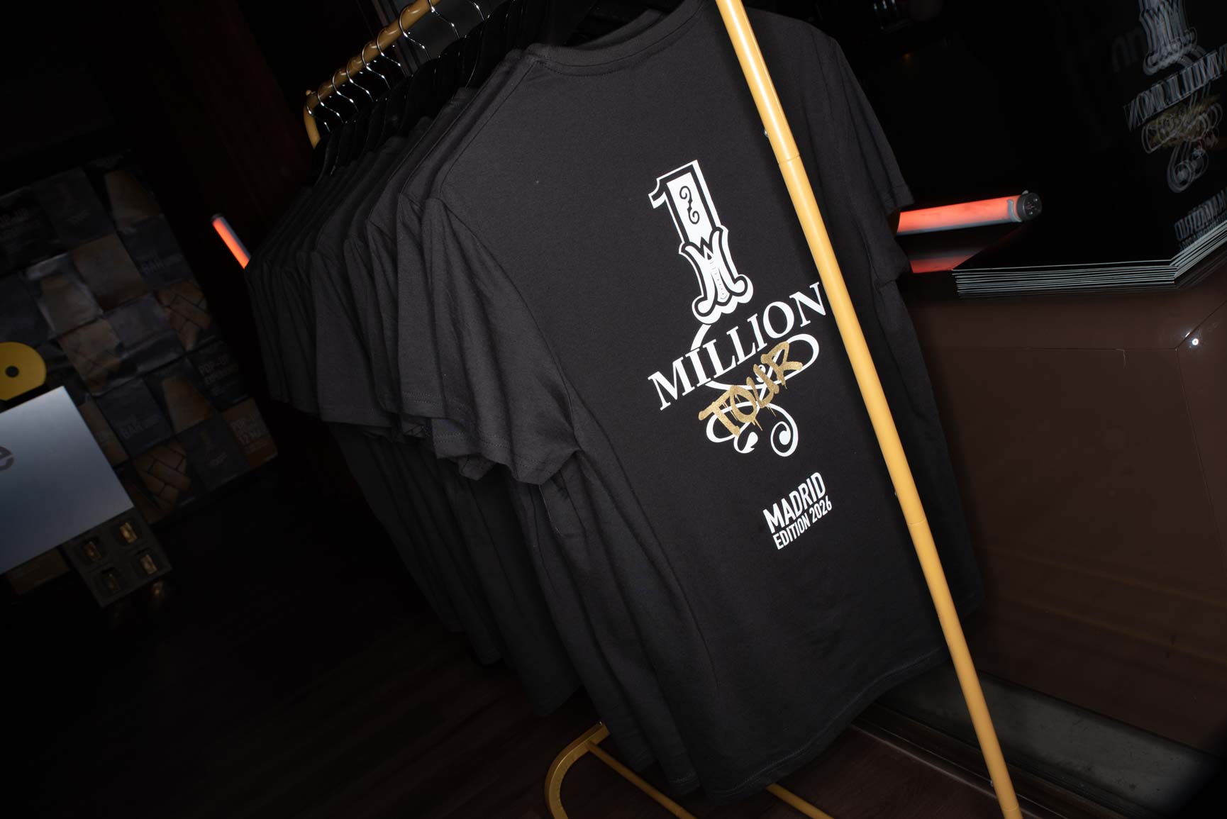 Black Rabanne One Million Madrid Edition 2026 t-shirt on gold rack, exclusive merchandise from the One Million Tour pop-up