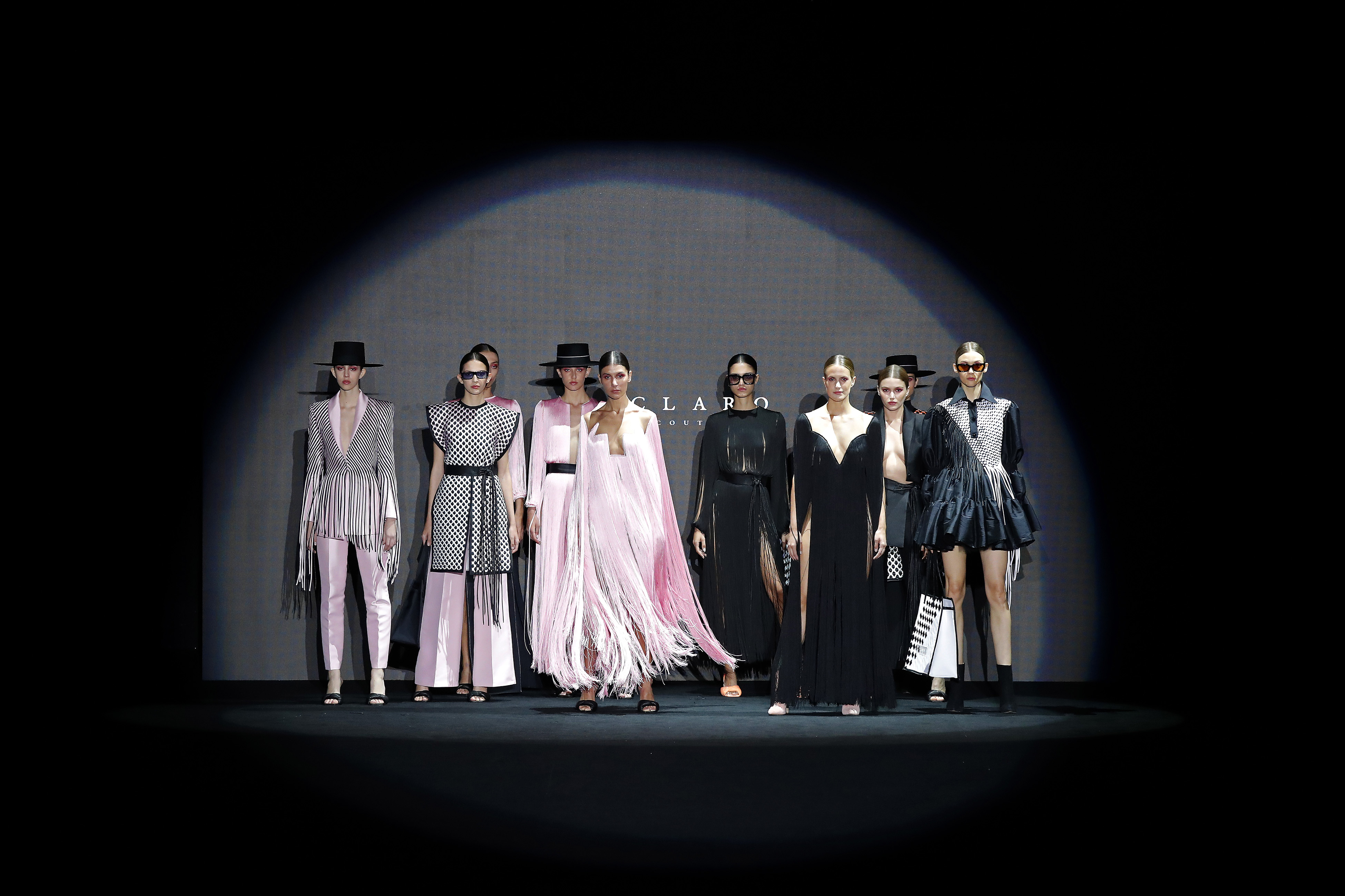 Grupo de modelos con sombreros y looks grises, rosas y negros posando dentro de un círculo de luz, Mercedes-Benz Fashion Week Madrid FW 2021 producida por ESMA Events