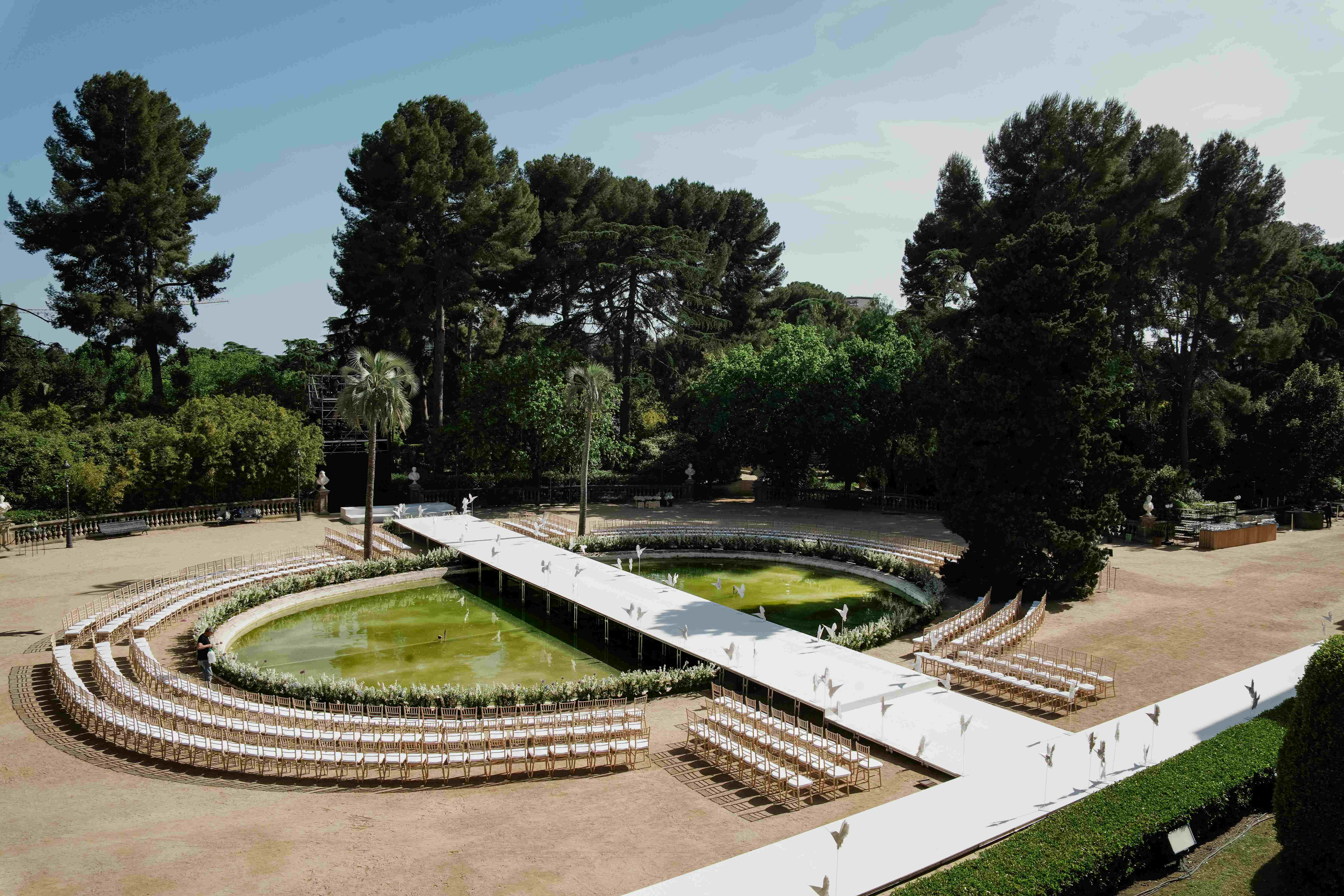 Vista aérea de los jardines del Palau Reial de Pedralbes con la pasarela blanca sobre el estanque y las gradas, desfile de Woná Concept & Eva Lendel producido por ESMA Events