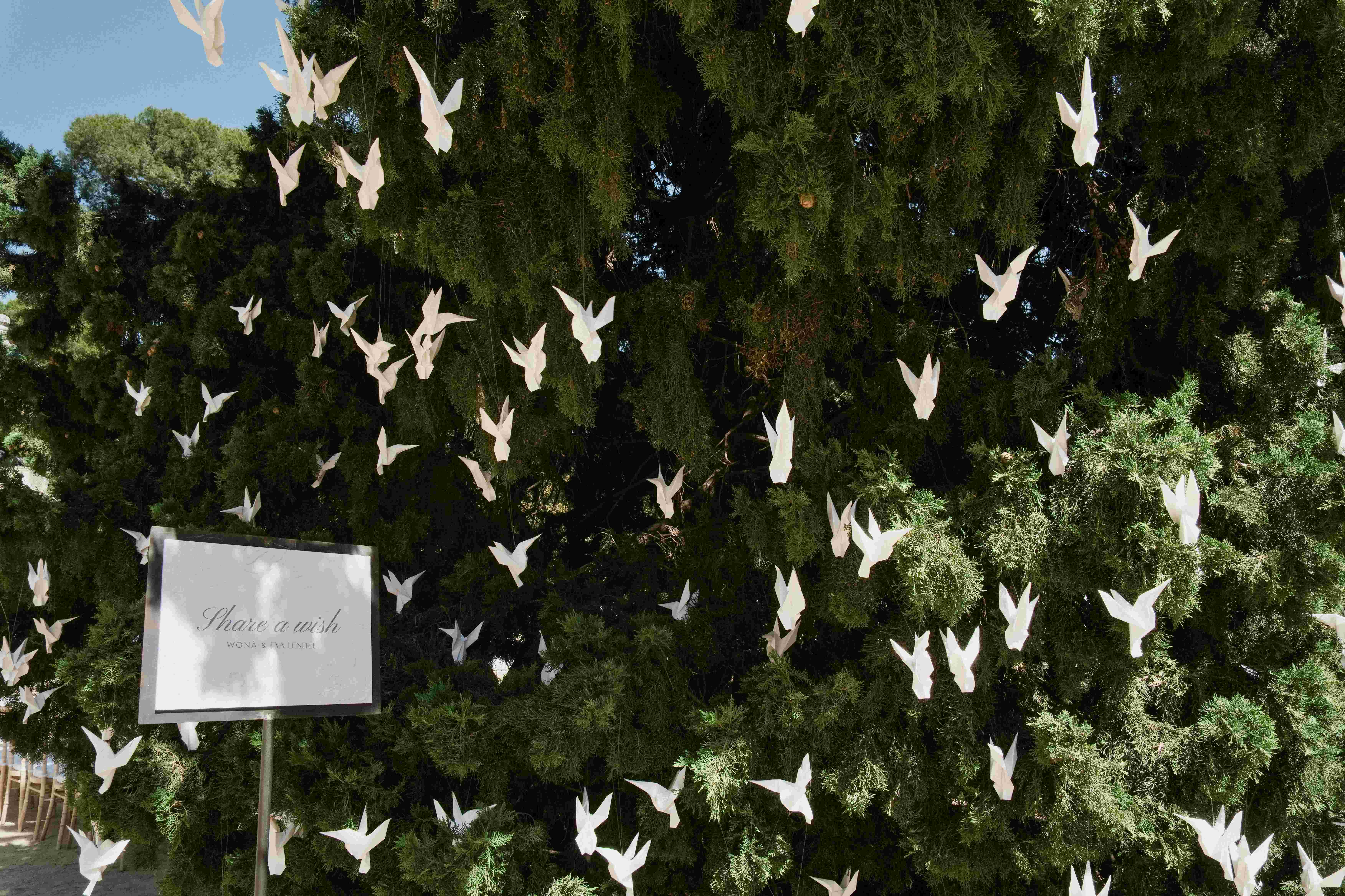 Pájaros de papel blancos sobre un seto y cartel de reserva, decoración del desfile de Woná Concept & Eva Lendel