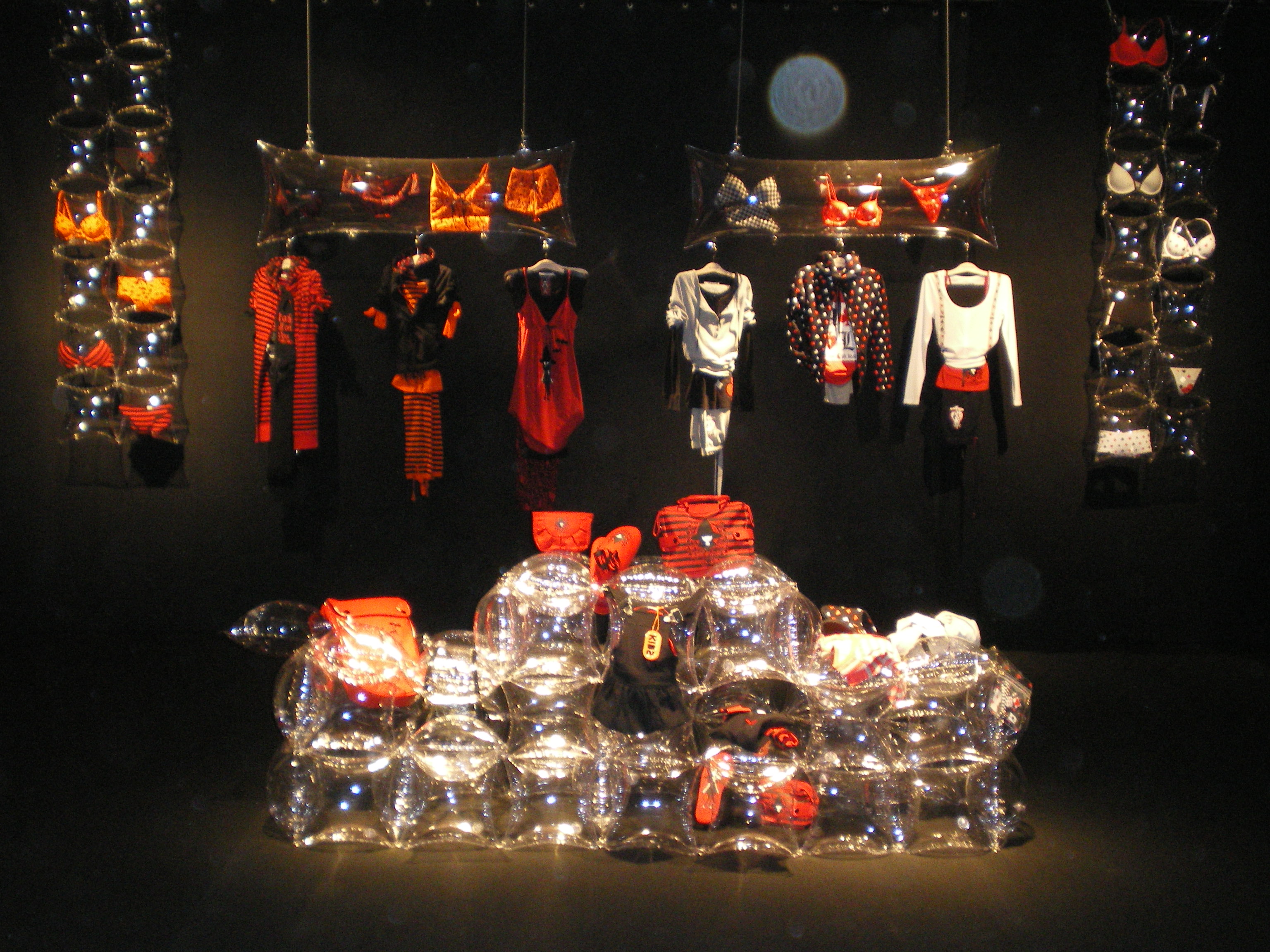 Illuminated display with red and white garments and lingerie hanging and a stack of glass containers, Women'secret September 2007 collection launch produced by ESMA Events