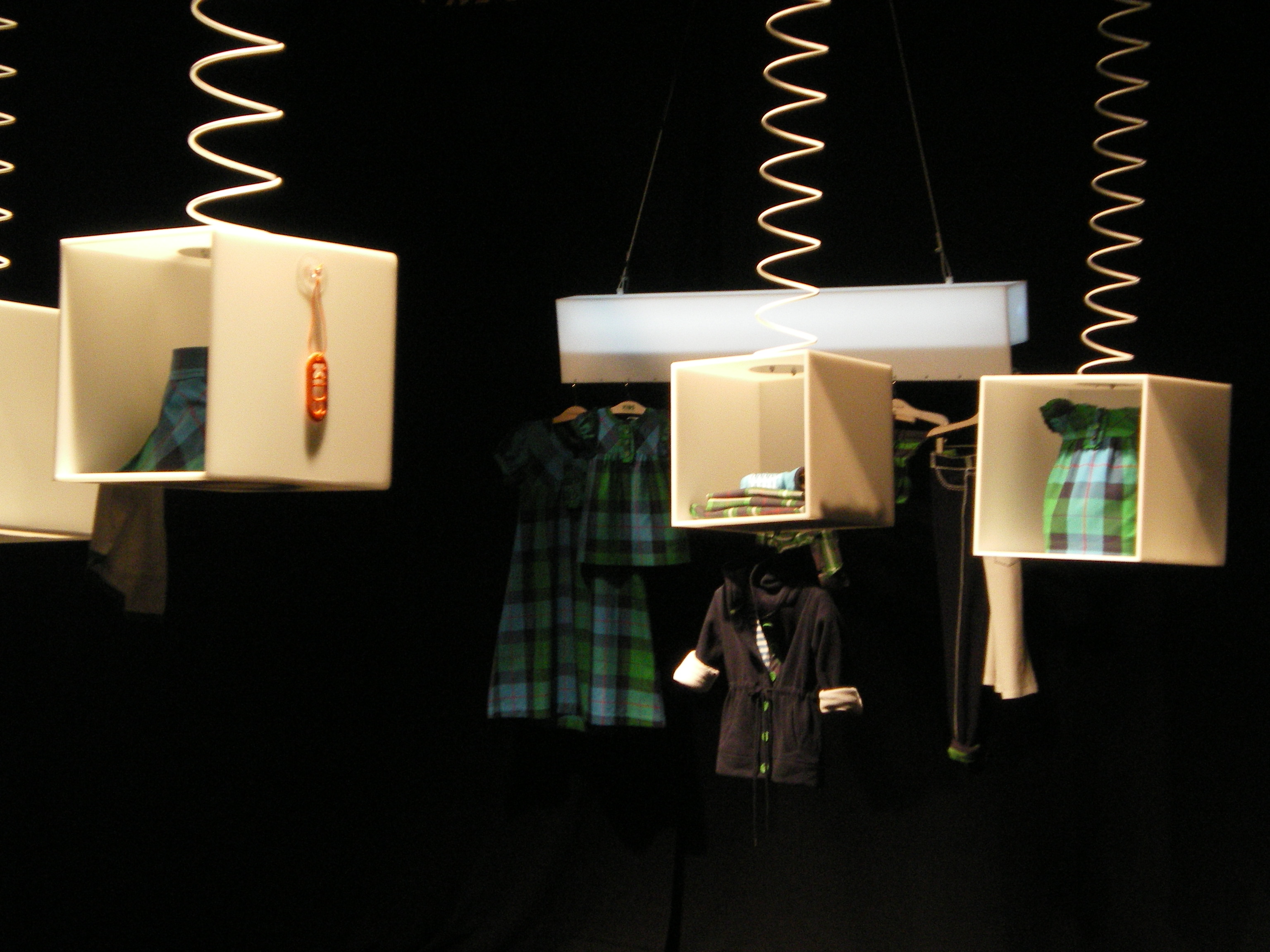 Hanging white boxes with green plaid garments and accessories on a black background, Women'secret September 2007 collection launch produced by ESMA Events