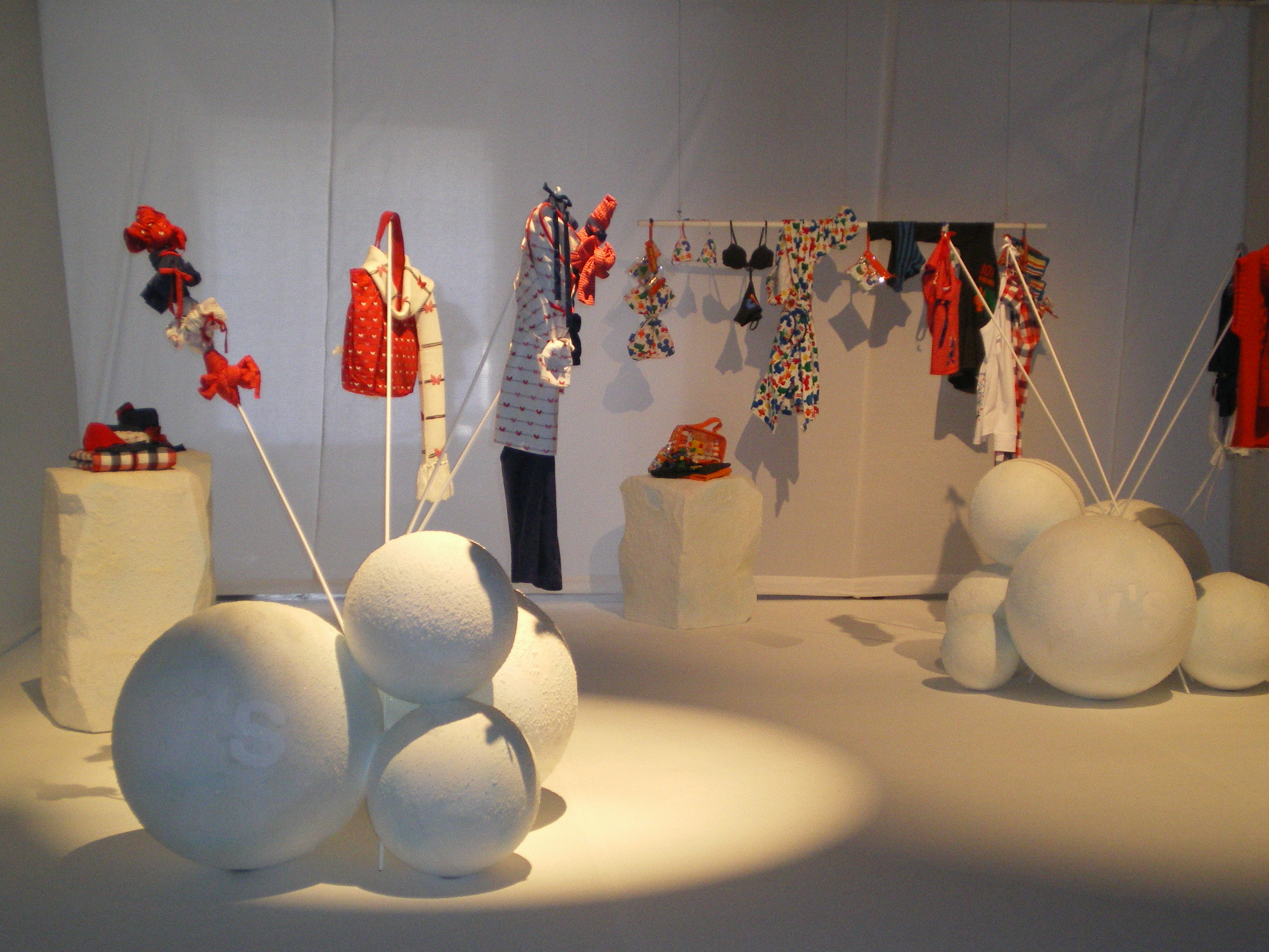 Large white spheres and racks with red and patterned garments on a white floor, Women'secret September 2007 collection launch produced by ESMA Events