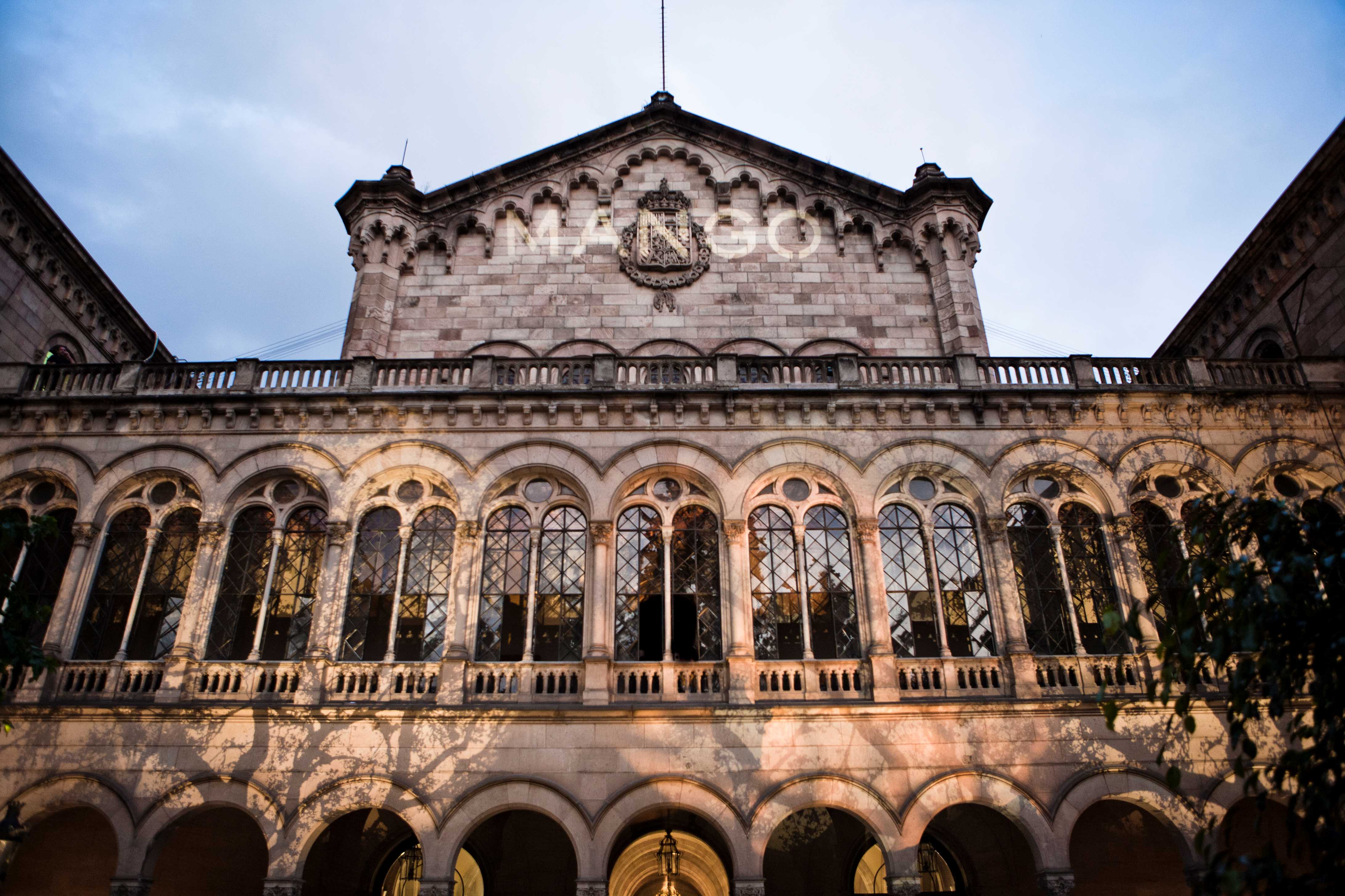 Fachada de un edificio histórico con ventanas en arco y el logotipo de Mango proyectado en el frontón, cocktail party de Mango producida por ESMA Events