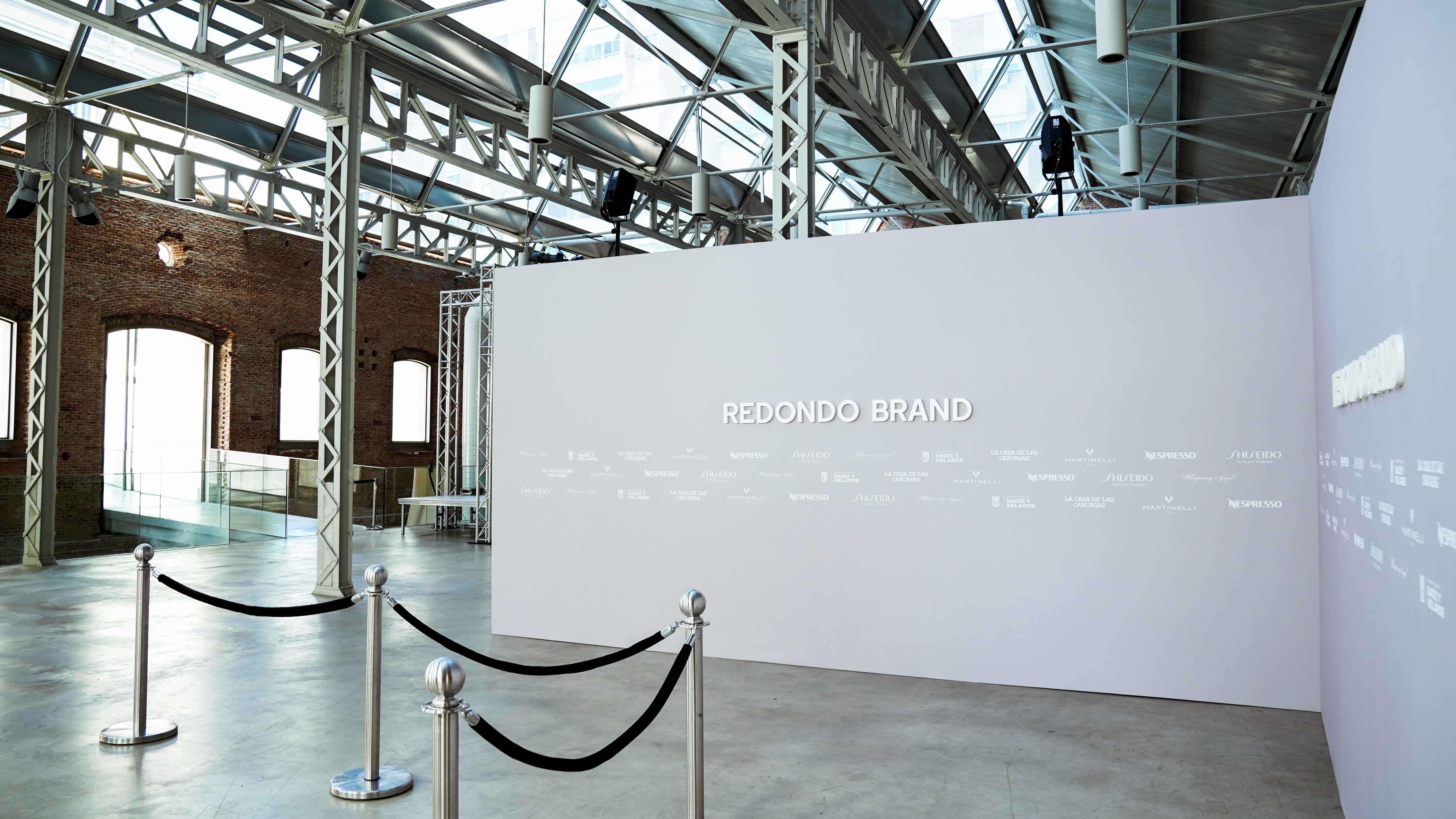 White wall with the Redondo Brand name and access ropes in a brick hall, Lola Flores Centenary exhibition by Redondo Brand produced by ESMA Events
