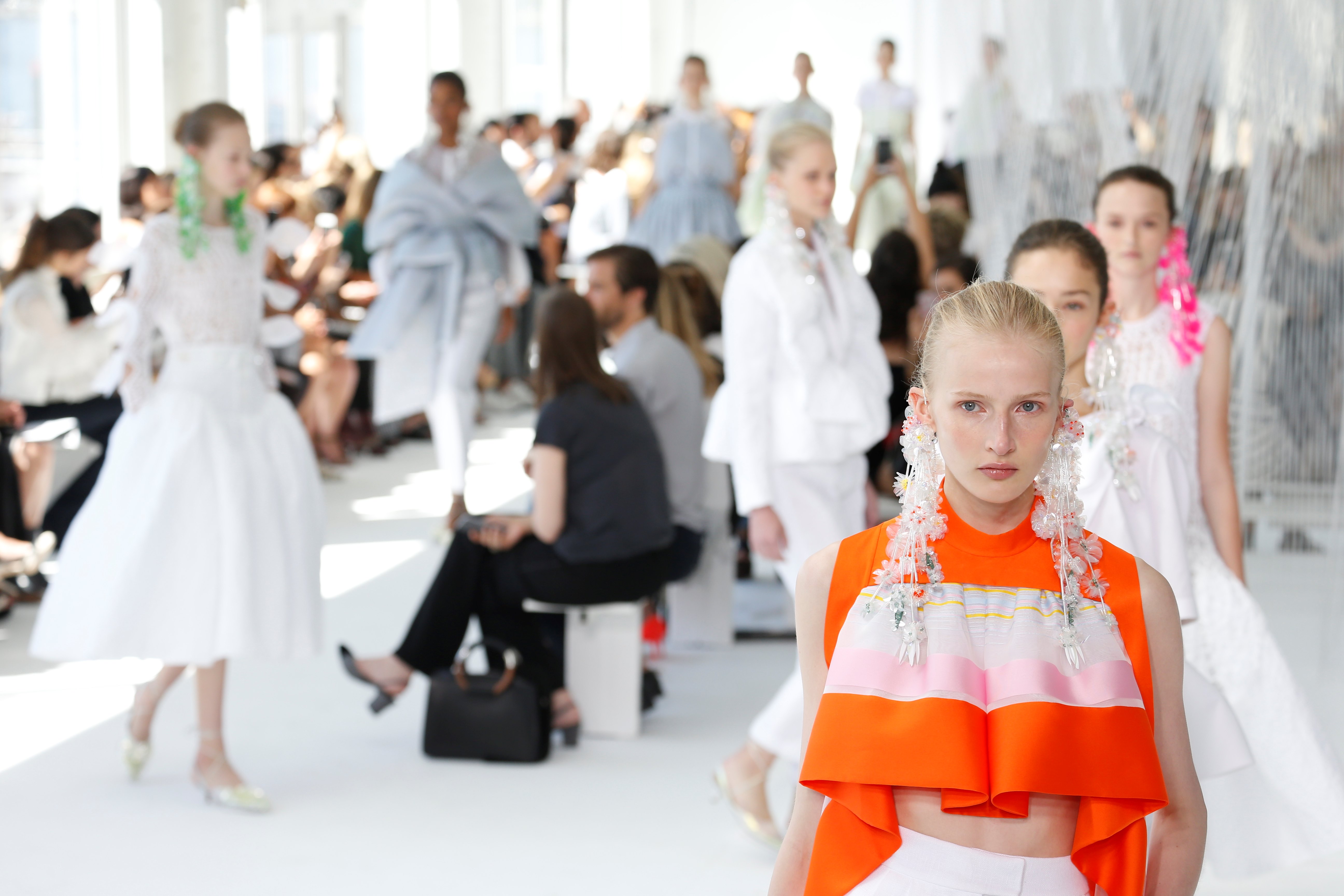Modelos con prendas blancas y naranjas en la pasarela, con el público a ambos lados, desfile Delpozo Nueva York SS 2017 producido por ESMA Events