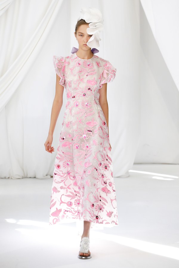 Modelo con vestido largo estampado en rosa y tocado blanco ante cortinas blancas, desfile Delpozo Londres SS 2019 producido por ESMA Events