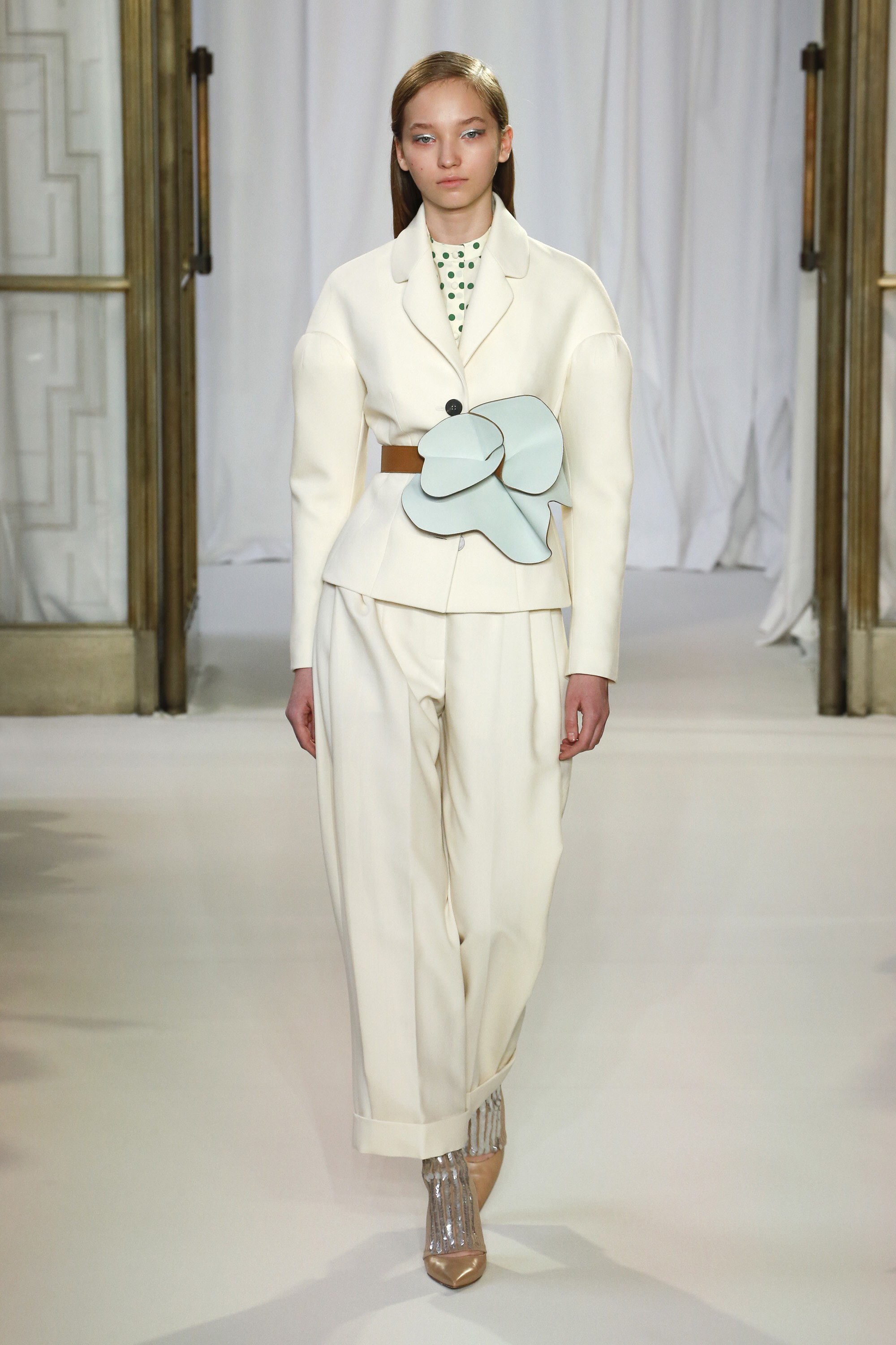 Model in an off-white suit with a light-blue leather flower at the waist, Delpozo London FW 2018 show produced by ESMA Events