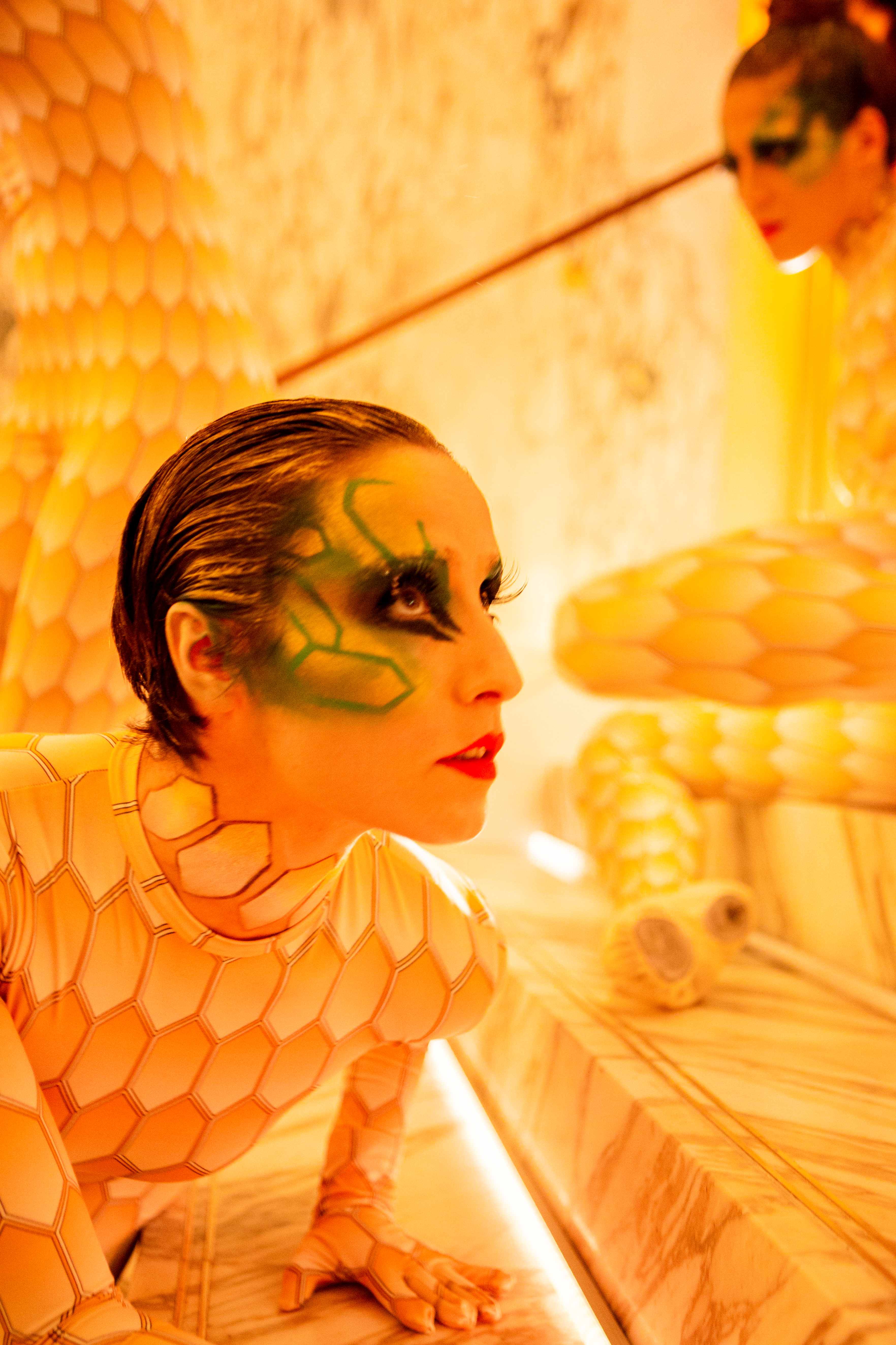 Intérprete con maquillaje verde y cuerpo pintado de escamas doradas en una sala naranja, inauguración de la boutique Bvlgari Serpenti de Barcelona producida por ESMA Events