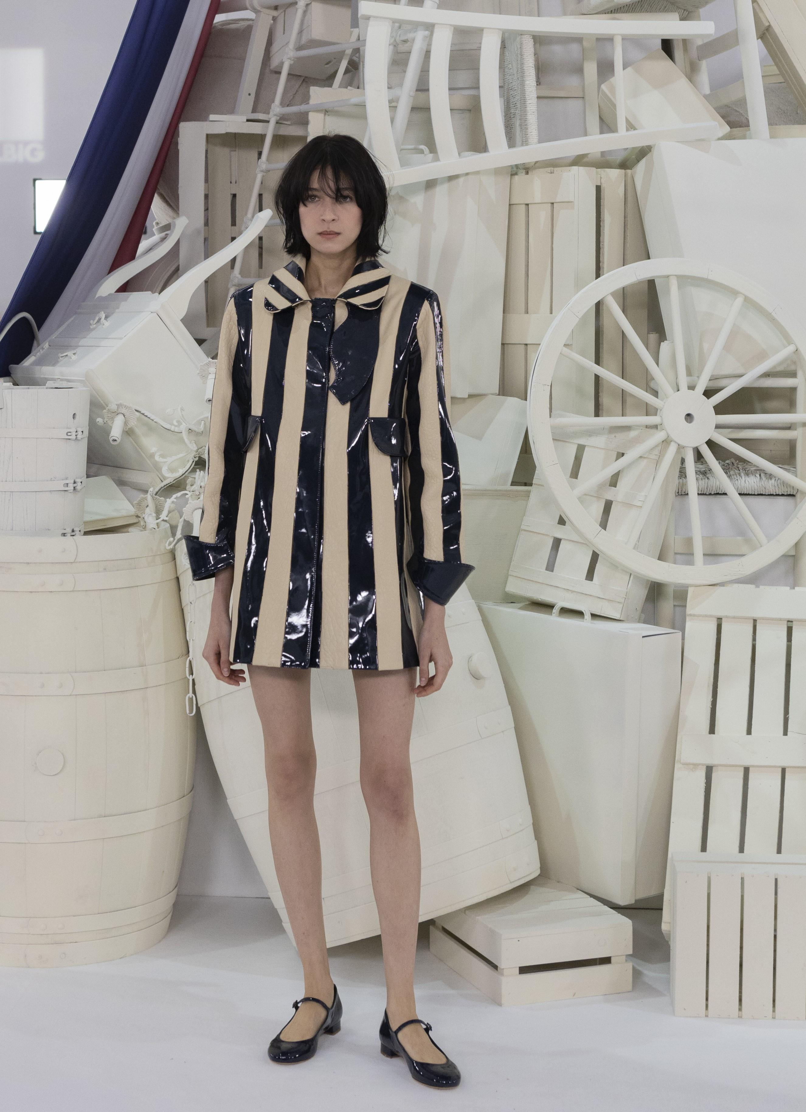 Model in a black and gold striped jacket and black shoes in front of the white installation, 1832 Sur Mer Teresa Helbig FW24/25 presentation produced by ESMA Events