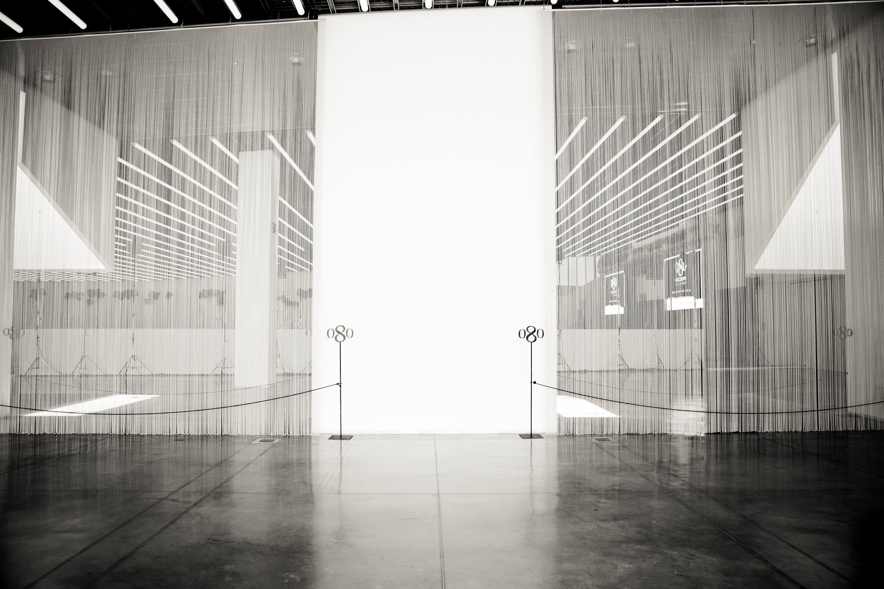 Sala de desfile vacía con cortinas de hilos blancos y focos de luz, en blanco y negro, 080 Barcelona Fashion SS 2014 producida por ESMA Events