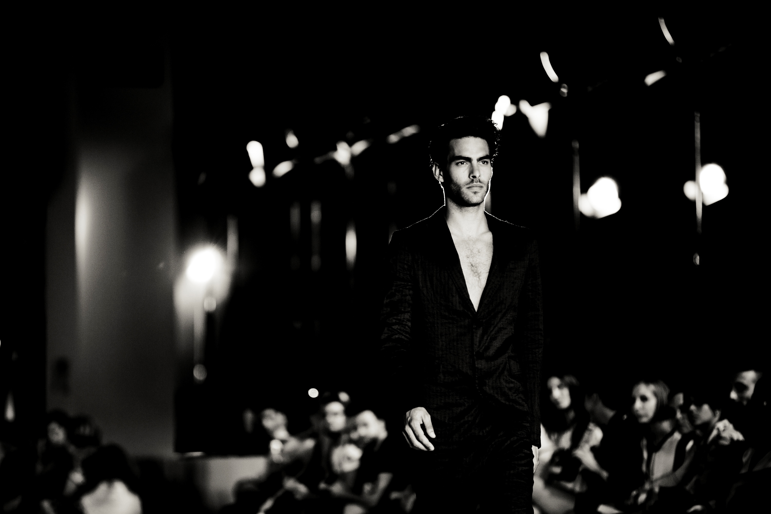 Modelo con traje oscuro caminando ante el público en la pasarela, en blanco y negro, 080 Barcelona Fashion SS 2014 producida por ESMA Events