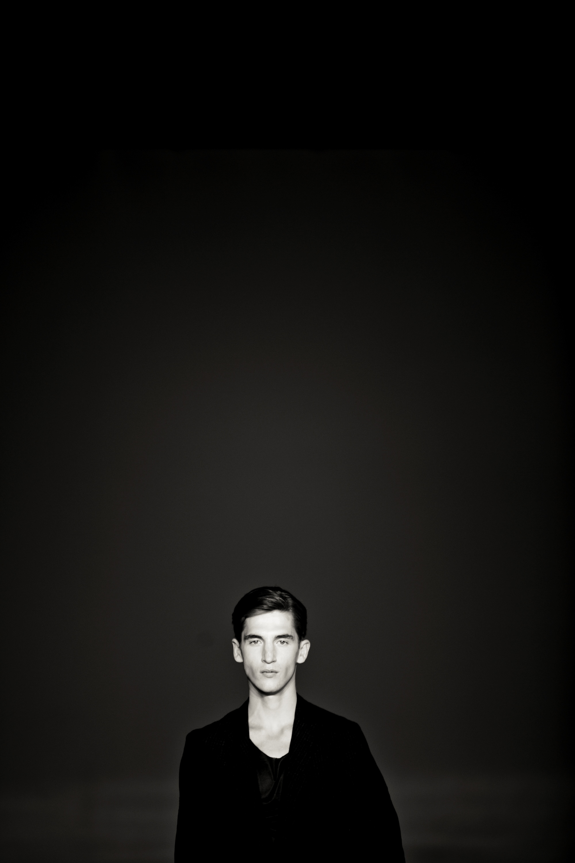 Modelo con chaqueta oscura sobre fondo negro, en blanco y negro, 080 Barcelona Fashion SS 2014 producida por ESMA Events