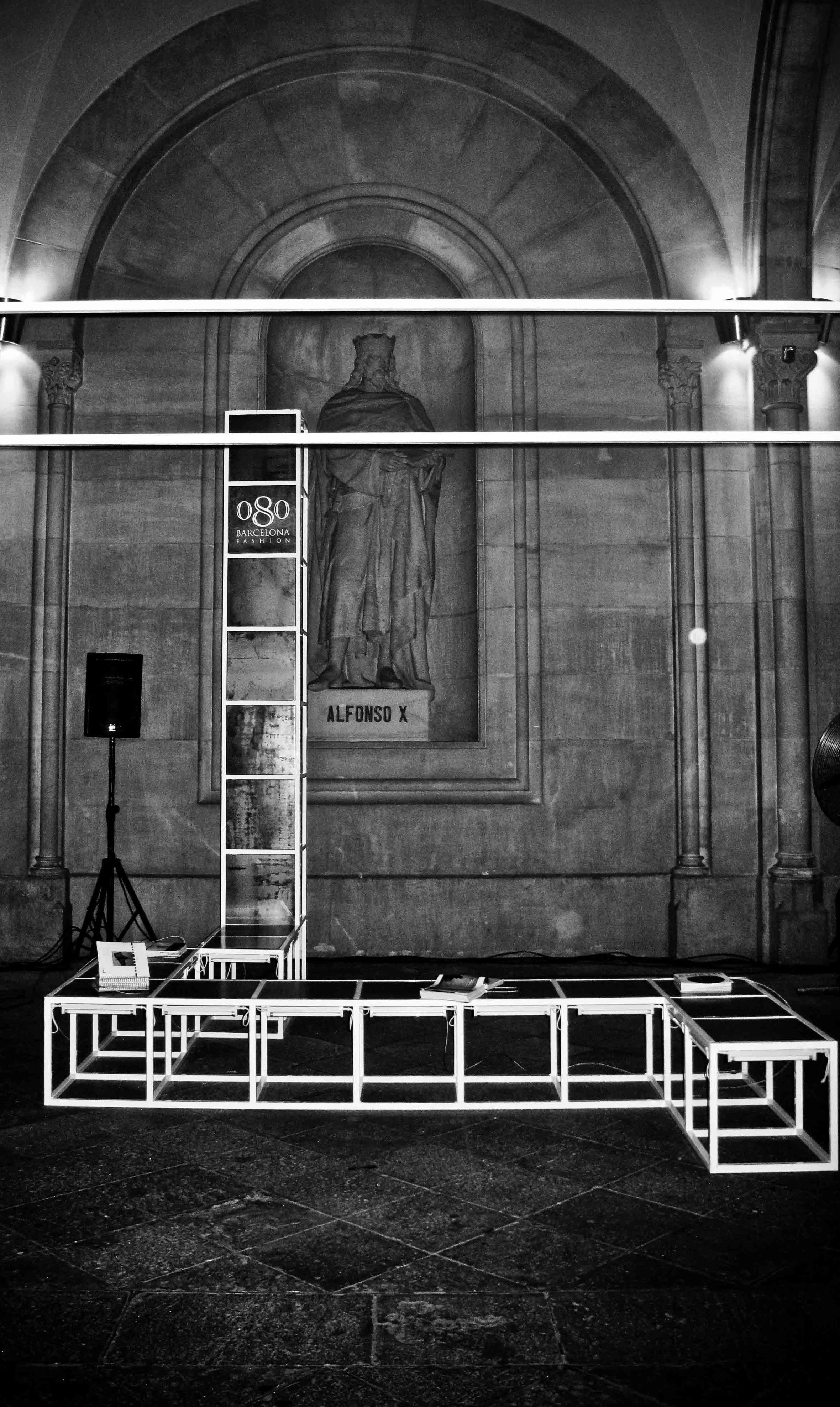 Estructura de tubos blancos y plataforma baja ante una pared con arco, en blanco y negro, 080 Barcelona Fashion SS 2012 producida por ESMA Events