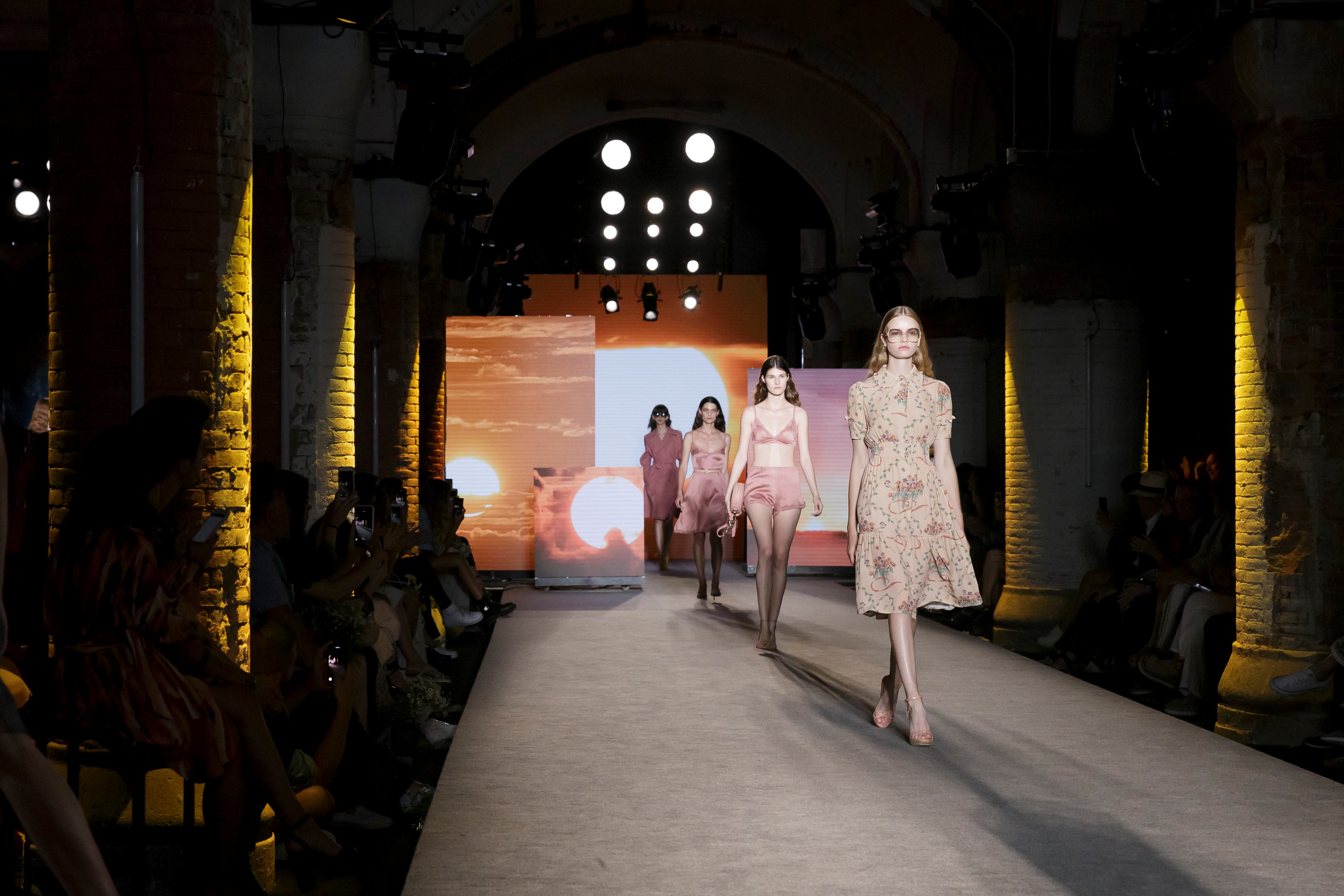 Modelos con vestidos rosas y beige desfilando por la pasarela entre columnas iluminadas en amarillo, 080 Barcelona Fashion SS 2019 producida por ESMA Events
