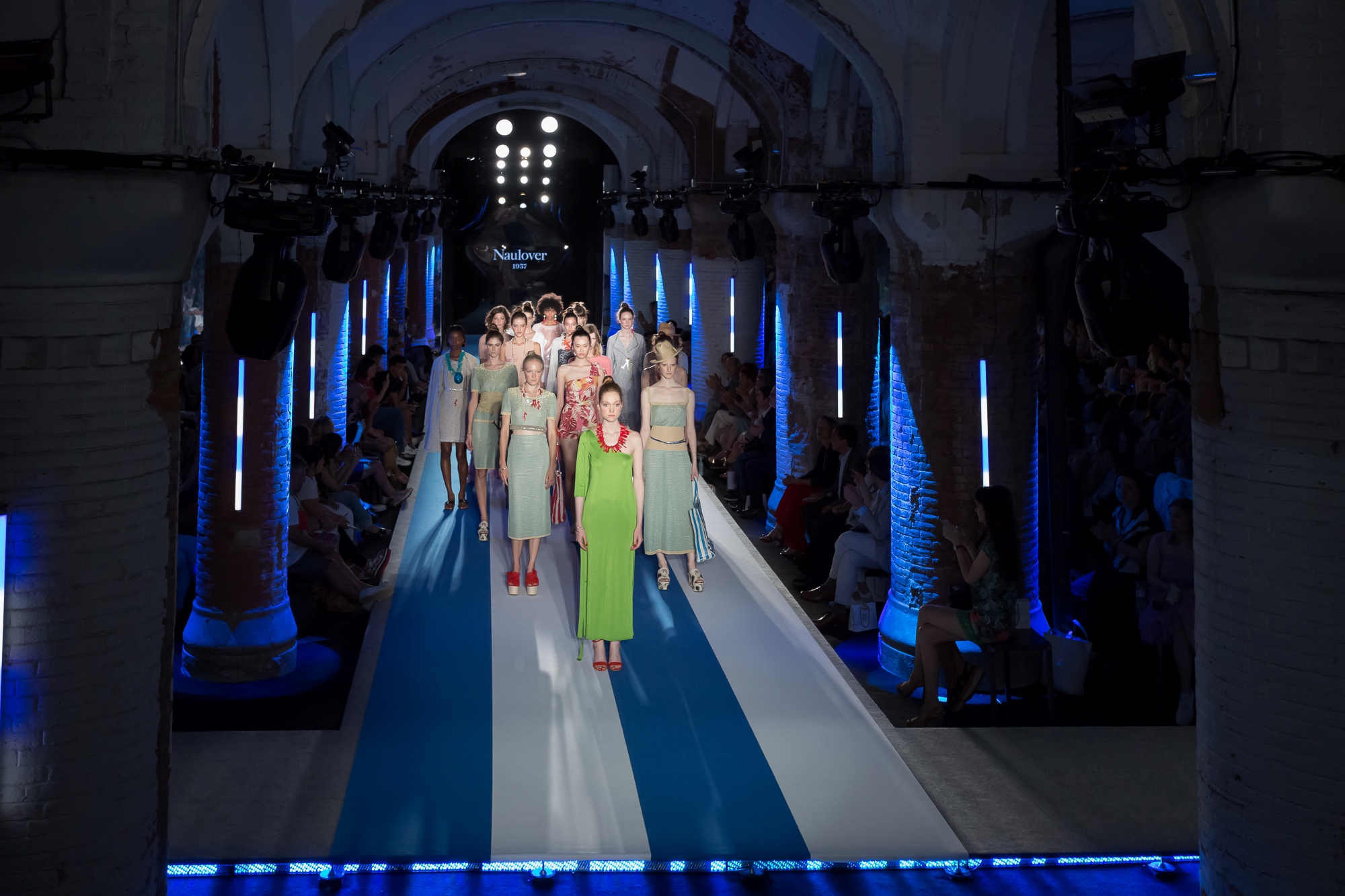 Final del desfile con modelos con looks verdes, rosas y claros sobre una pasarela con rayas azules, 080 Barcelona Fashion SS 2019 producida por ESMA Events