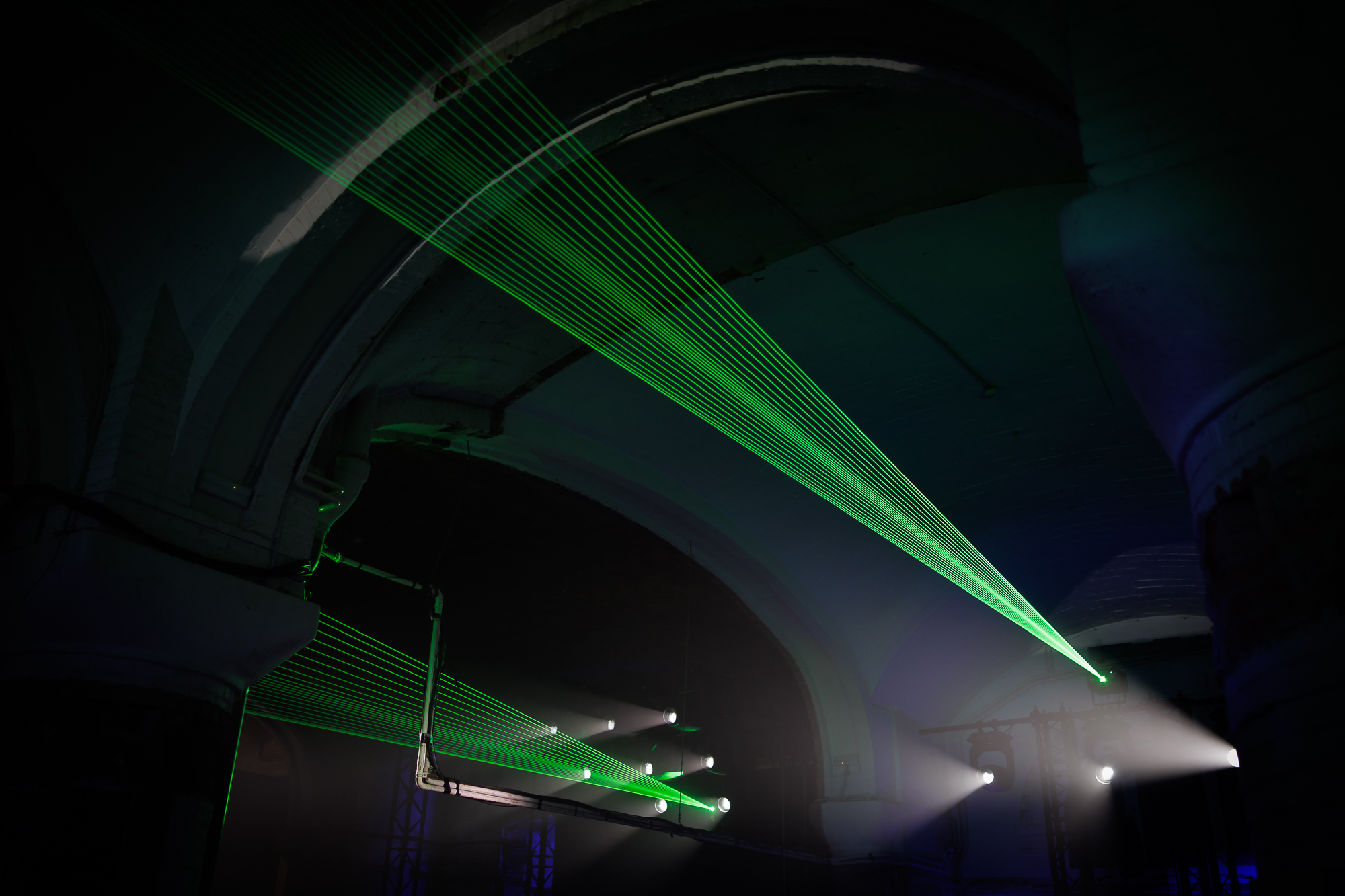 Rayos láser verdes cruzando una sala de bóvedas oscura, 080 Barcelona Fashion FW 2024-2025 producida por ESMA Events