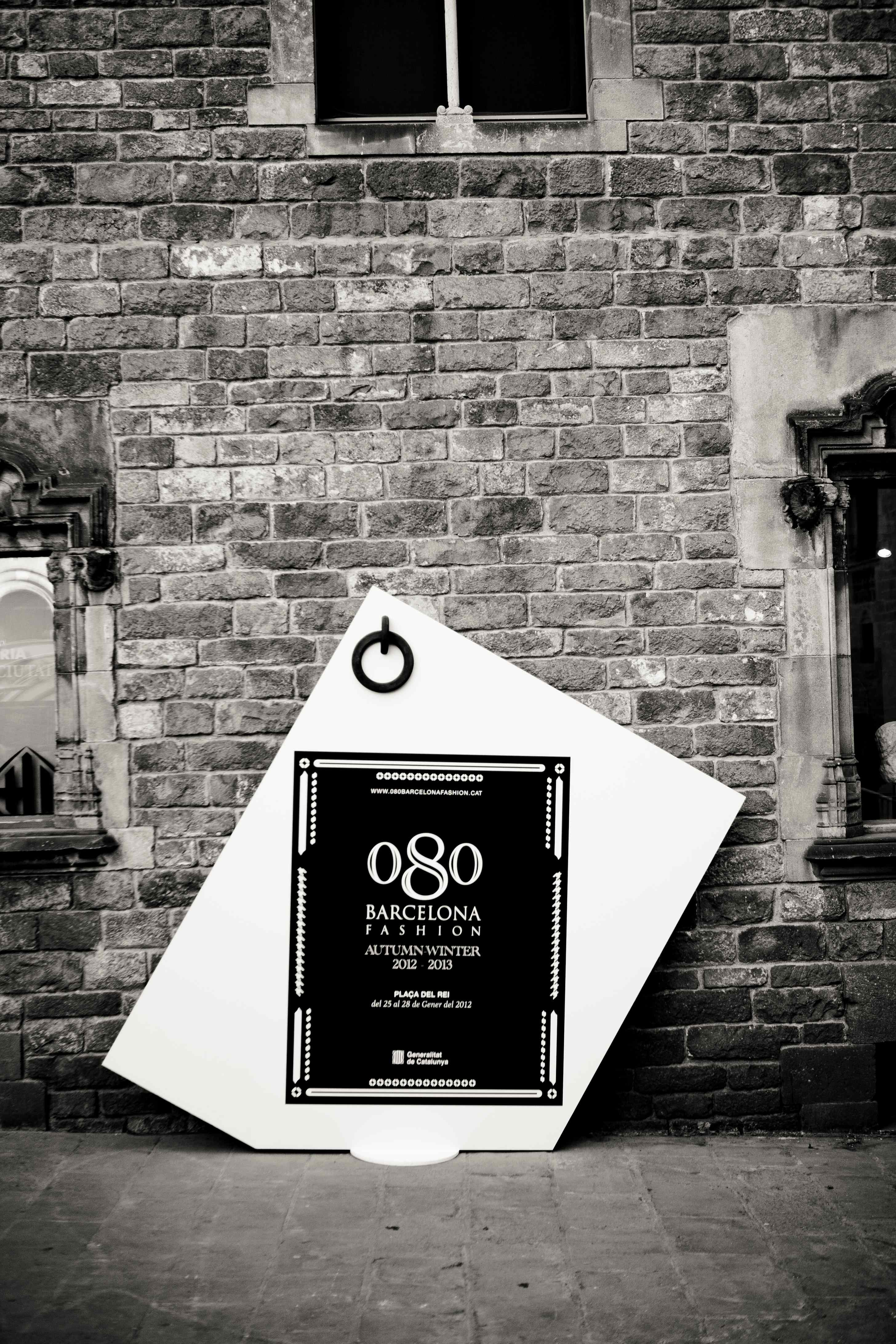 Cartel del 080 Barcelona Fashion apoyado contra una pared de ladrillo, en blanco y negro, 080 Barcelona Fashion FW 2012-2013 producida por ESMA Events