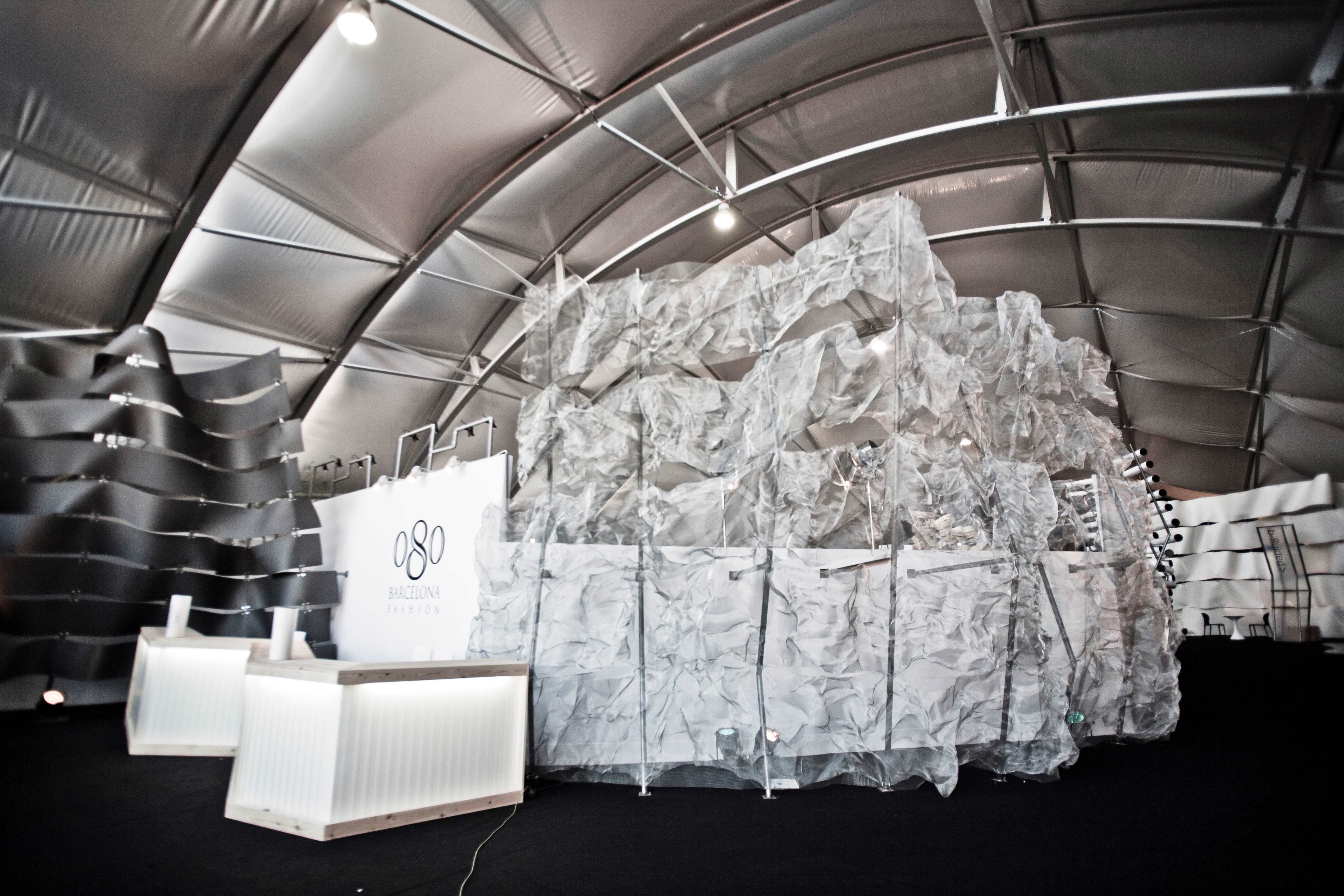 Instalación de papel arrugado blanco bajo la carpa metálica, con un mostrador y el logotipo 080, 080 Barcelona Fashion FW 2011-2012 producida por ESMA Events