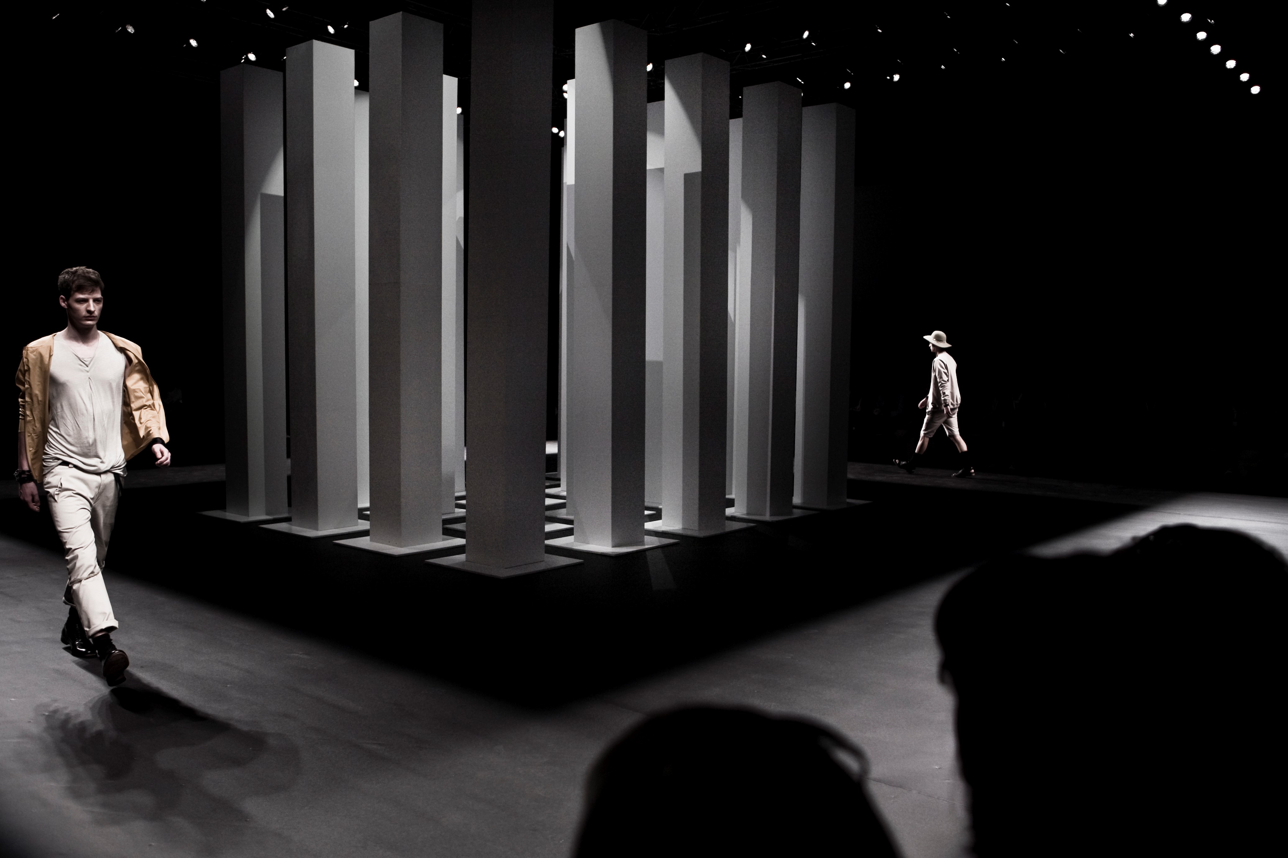 Dos modelos cruzando la pasarela entre columnas blancas sobre fondo negro, 080 Barcelona Fashion FW 2010-2011 producida por ESMA Events