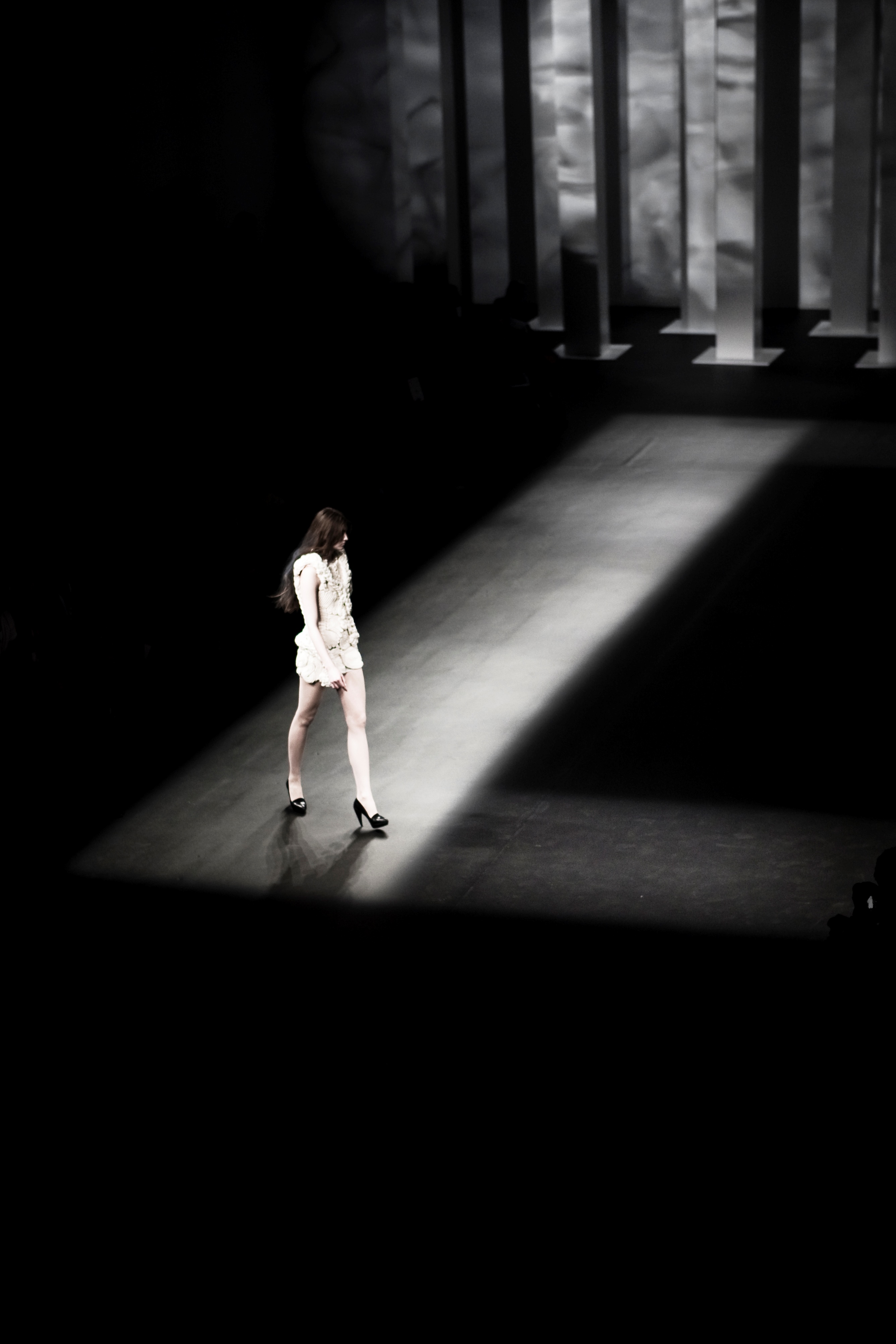Modelo con mono blanco caminando por una franja de luz en la pasarela oscura, 080 Barcelona Fashion FW 2010-2011 producida por ESMA Events