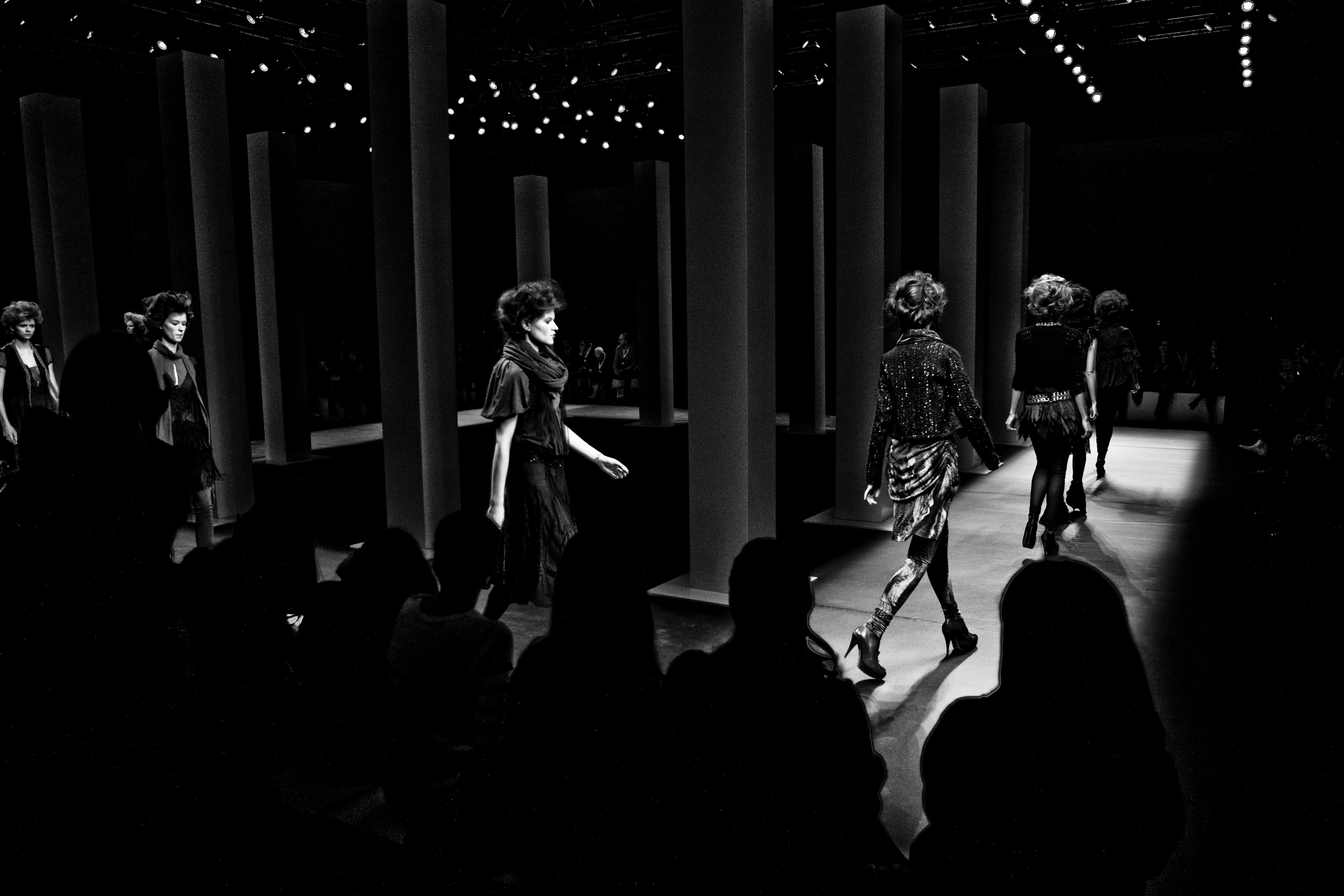 Modelos desfilando entre columnas ante un público en sombra, en blanco y negro, 080 Barcelona Fashion FW 2010-2011 producida por ESMA Events
