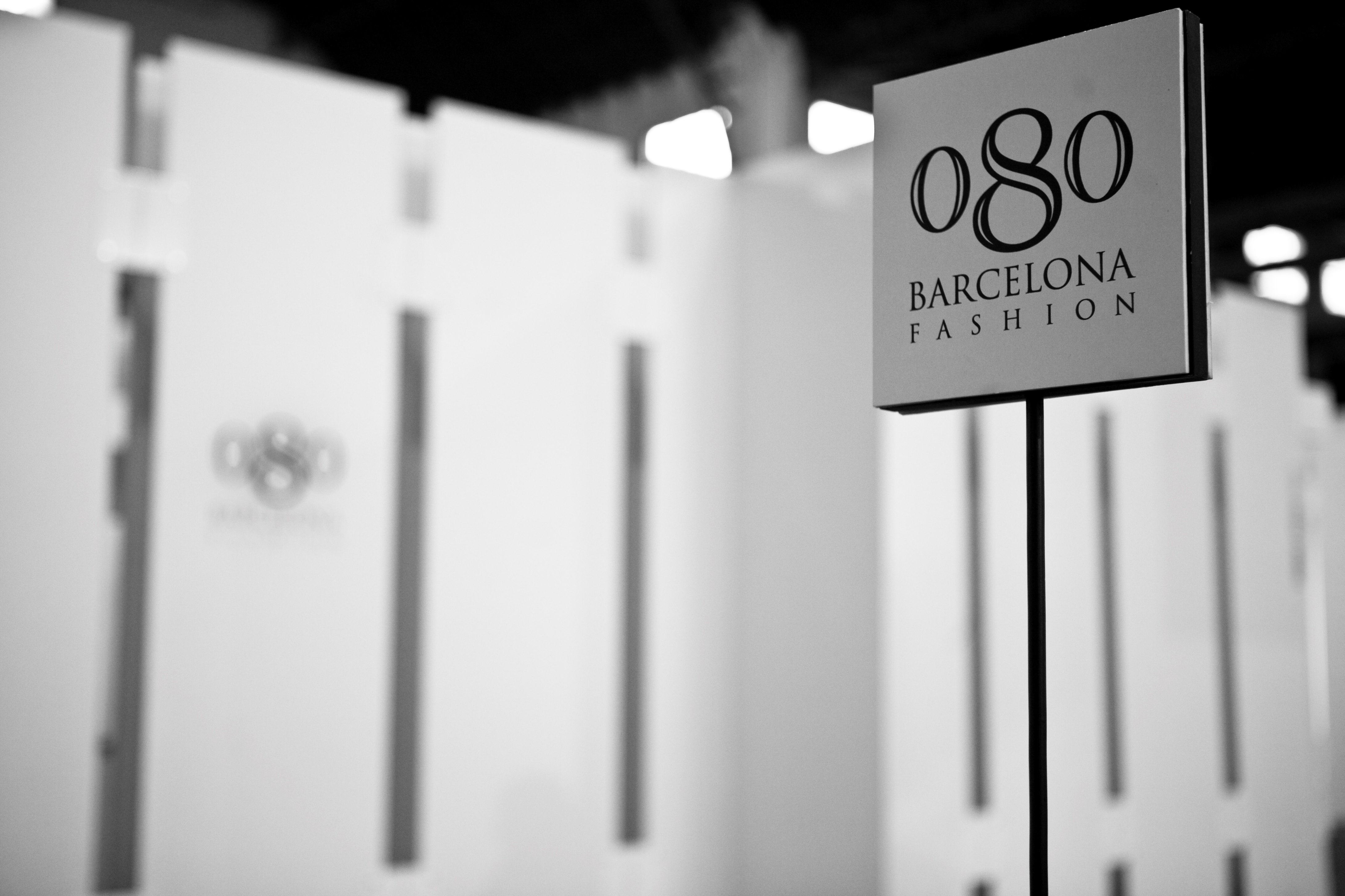 Cartel 080 Barcelona Fashion sobre un poste junto a paneles blancos, en blanco y negro, 080 Barcelona Fashion FW 2010-2011 producida por ESMA Events