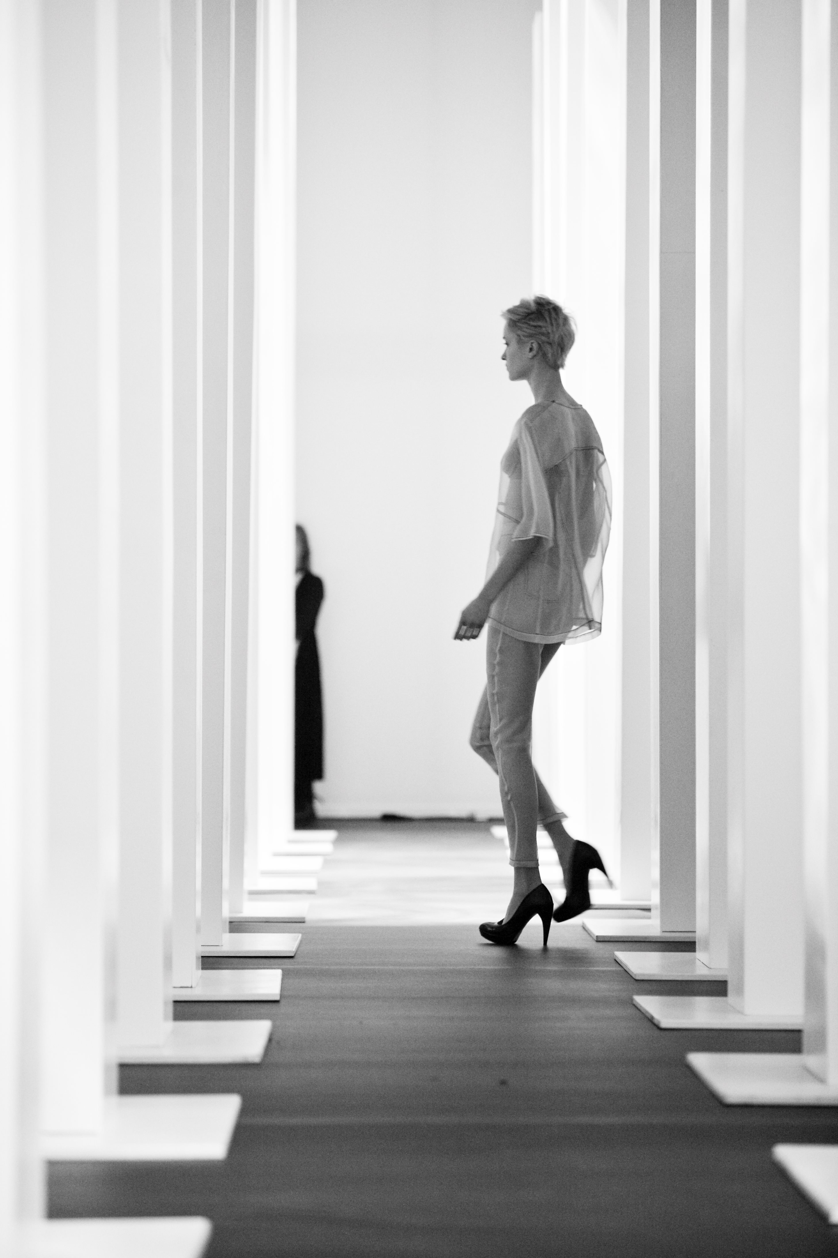 Modelo caminando por un pasillo entre columnas blancas, en blanco y negro, 080 Barcelona Fashion FW 2010-2011 producida por ESMA Events