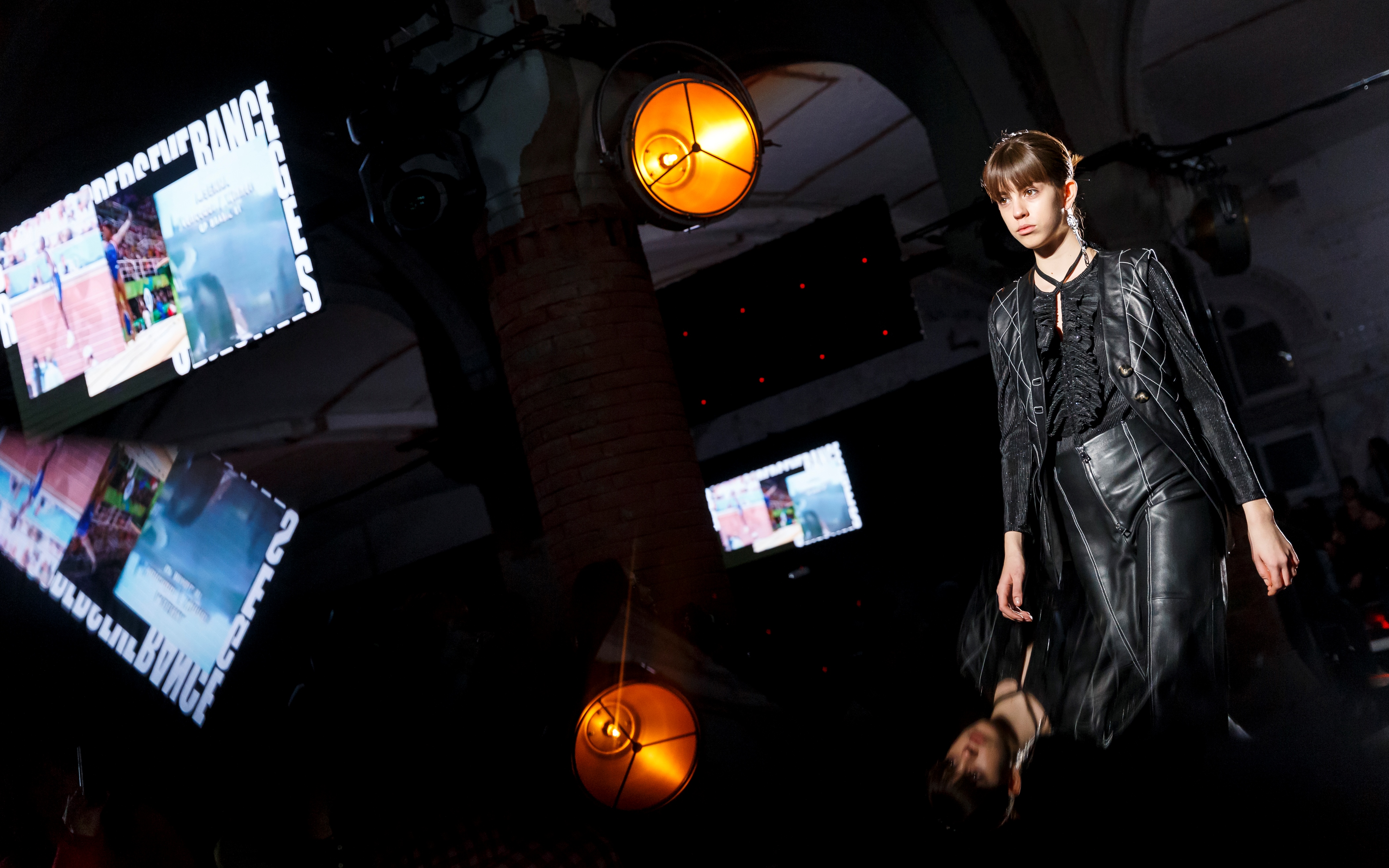Modelo con vestido de cuero negro con pantallas y lámparas reflejadas en la pasarela, 080 Barcelona Fashion FW 2018-2019 producida por ESMA Events