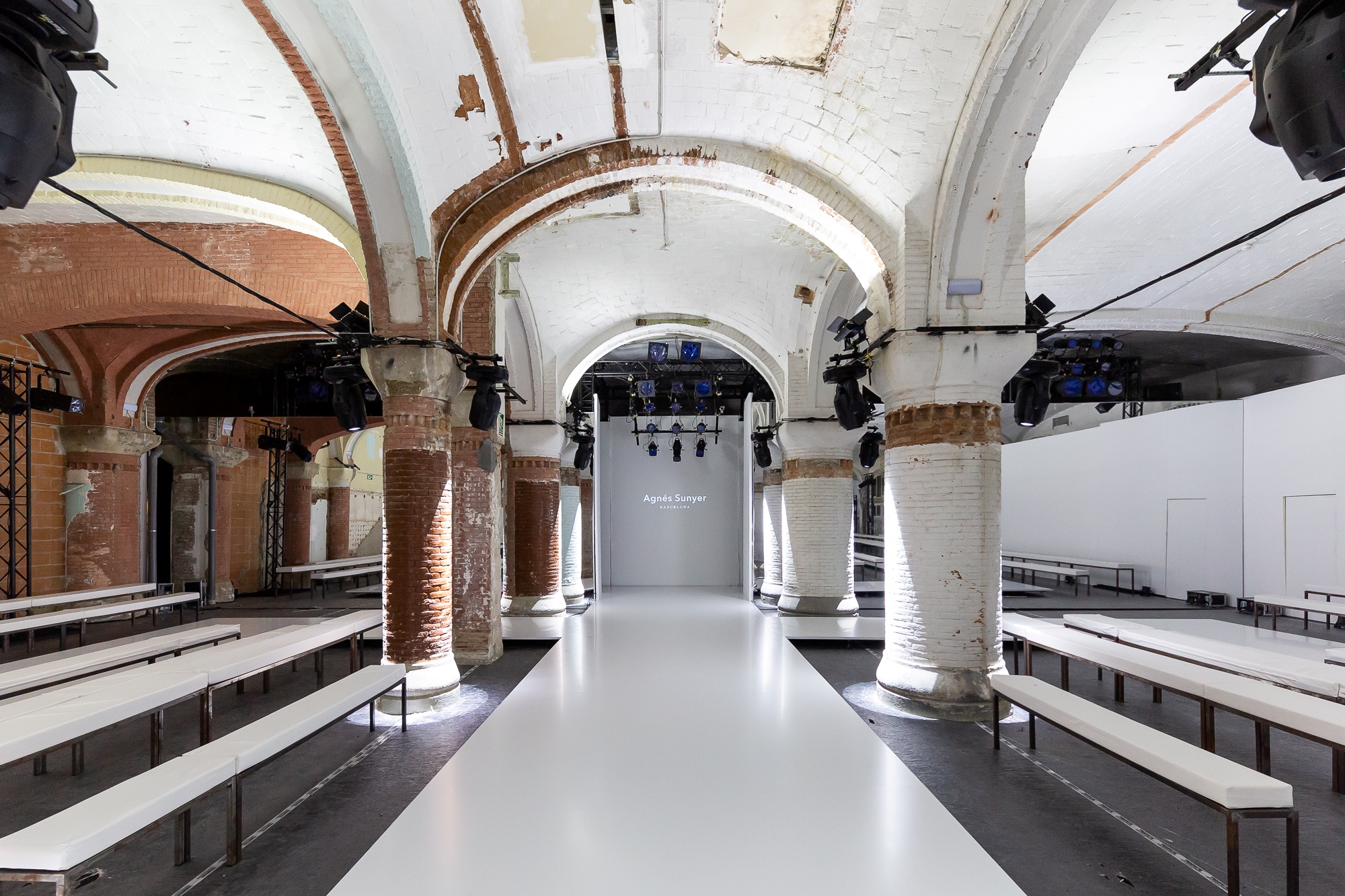 Pasarela blanca vacía entre gradas bajo bóvedas de ladrillo, 080 Barcelona Fashion FW 2019-2020 producida por ESMA Events
