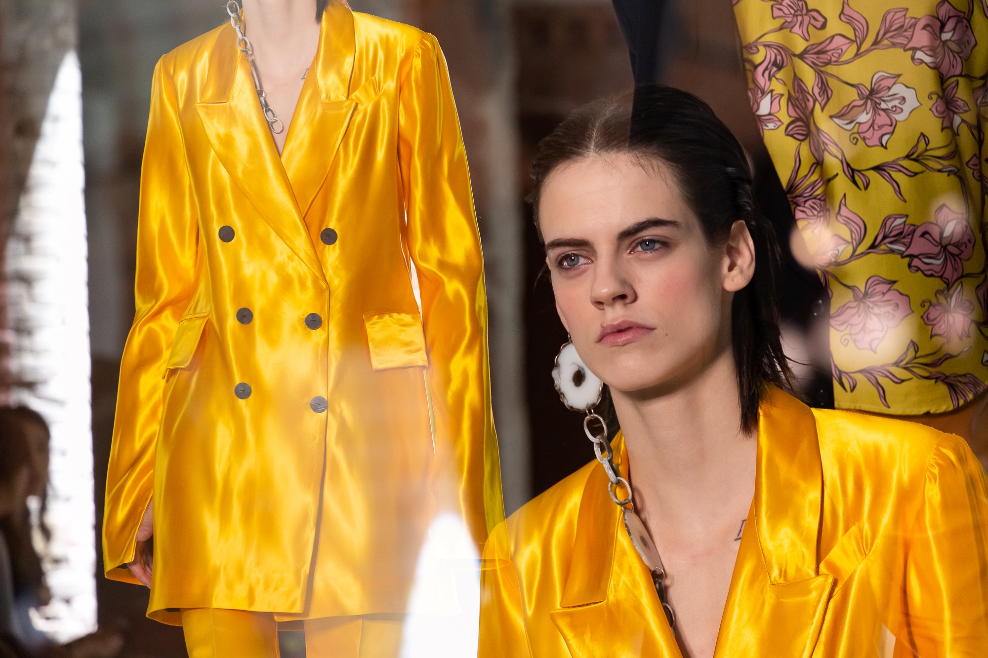 Retrato de una modelo con traje amarillo satinado junto a otra con estampado floral, 080 Barcelona Fashion FW 2019-2020 producida por ESMA Events