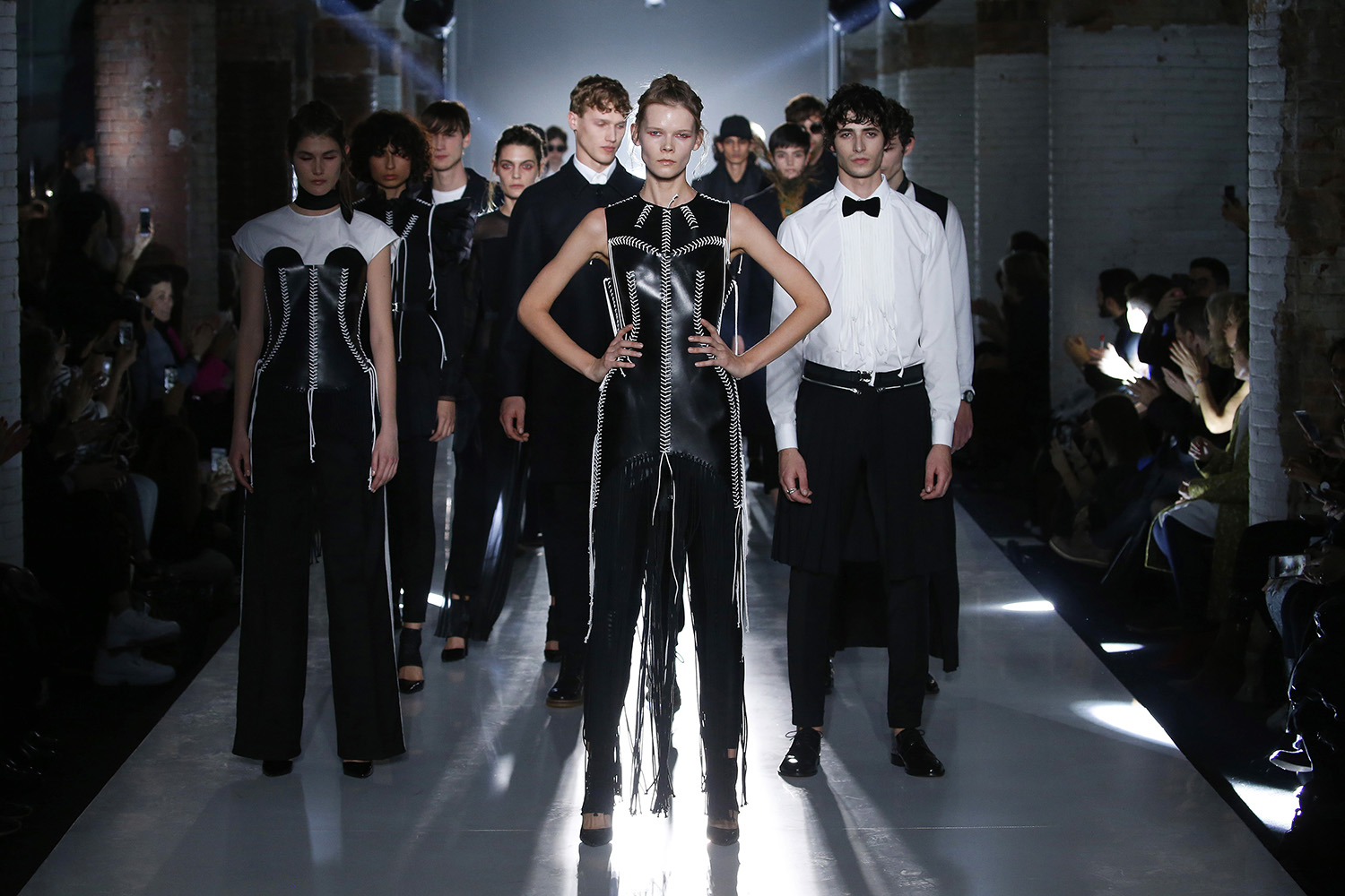 Modelos con prendas negras desfilando juntos por la pasarela iluminada a contraluz, 080 Barcelona Fashion FW 2019-2020 producida por ESMA Events