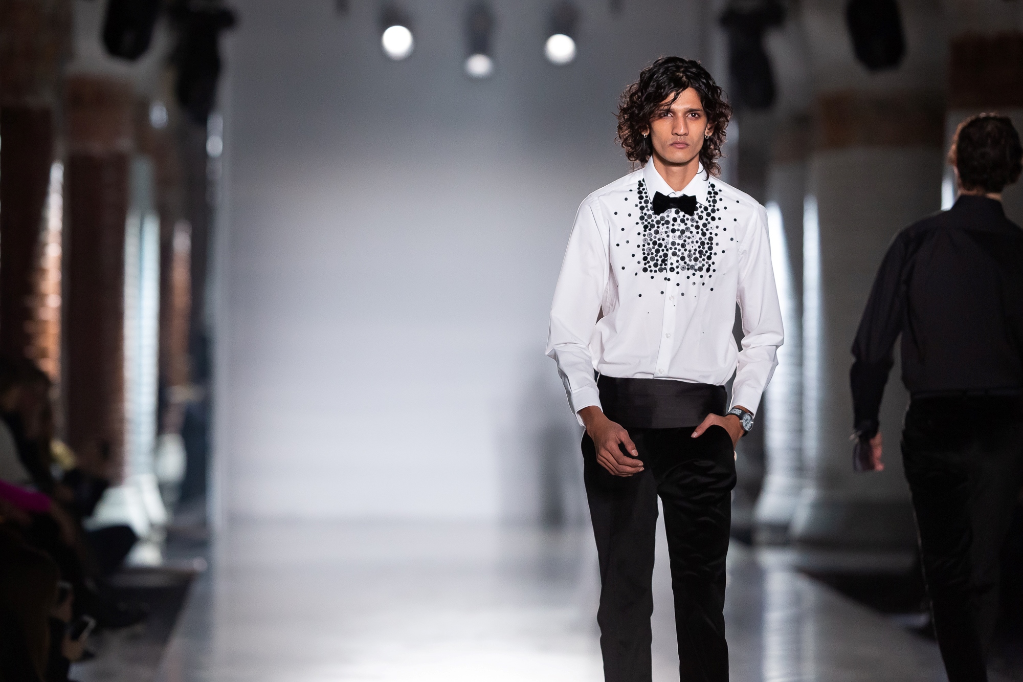 Modelo con camisa blanca bordada y fajín negro desfilando sobre la pasarela, 080 Barcelona Fashion FW 2019-2020 producida por ESMA Events