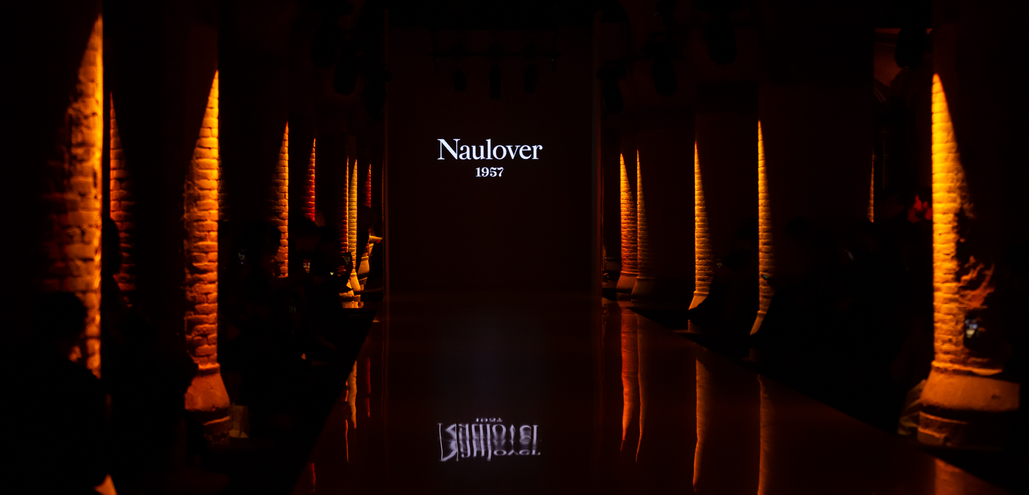 Pasarela con el nombre Naulover 1937 al fondo entre columnas de ladrillo iluminadas en naranja, 080 Barcelona Fashion FW 2019-2020 producida por ESMA Events