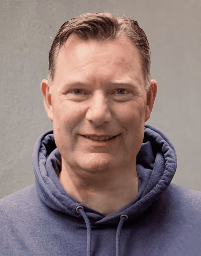 Porträt von Christian Hegel, CEO bei kaayo, in blauem Kapuzenpullover vor grauer Betonwand.