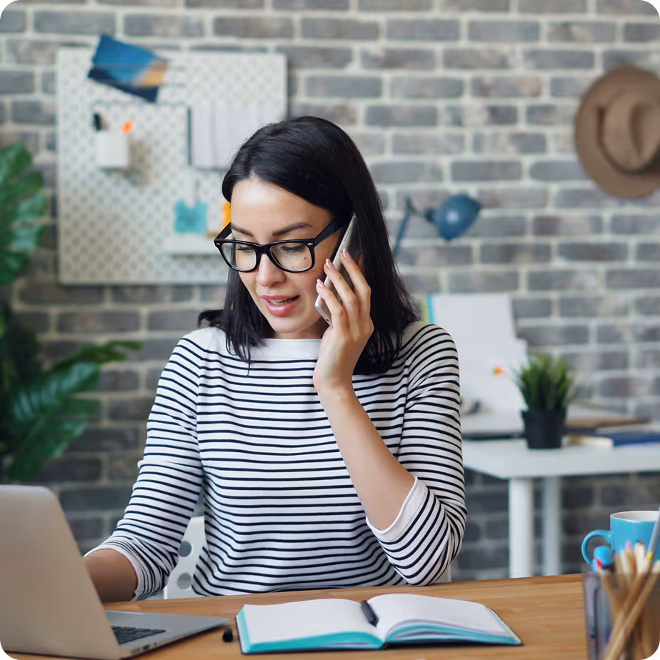 Two nonprofit workers sorting donated clothes indoors, one checking a clipboard and the other unpacking a box.