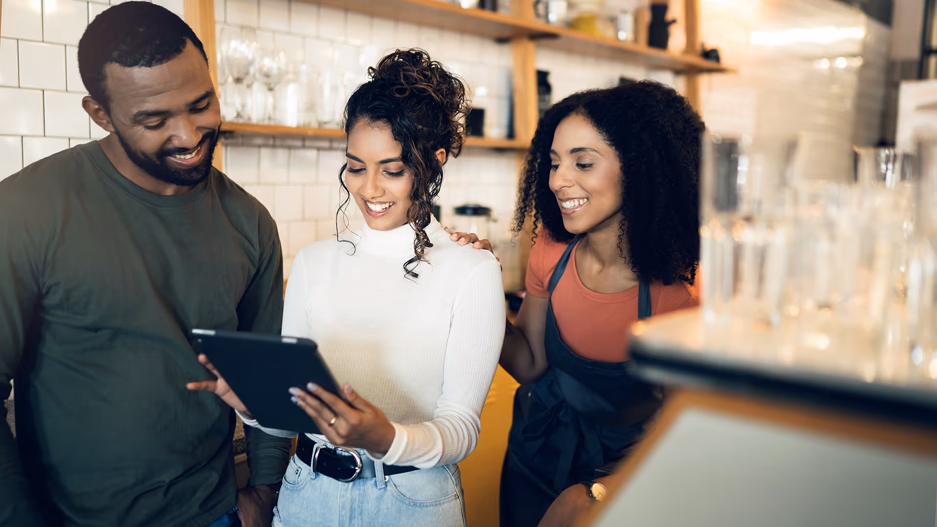 Three colleagues use a tablet to review payroll services for their restaurant. 
