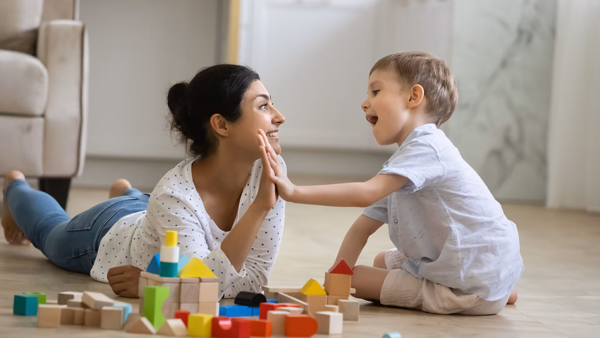 A nanny or babysitter plays and cares for a child in its home. 