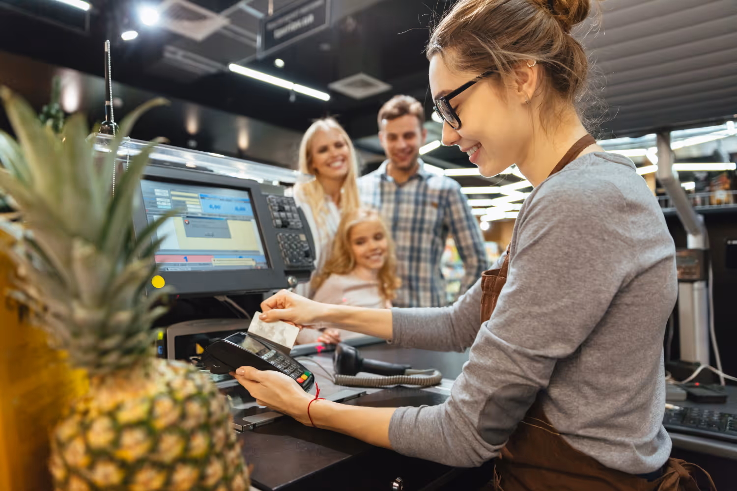 Cashier ringing up groceries for happy family_Image by drobotdean on Freepik