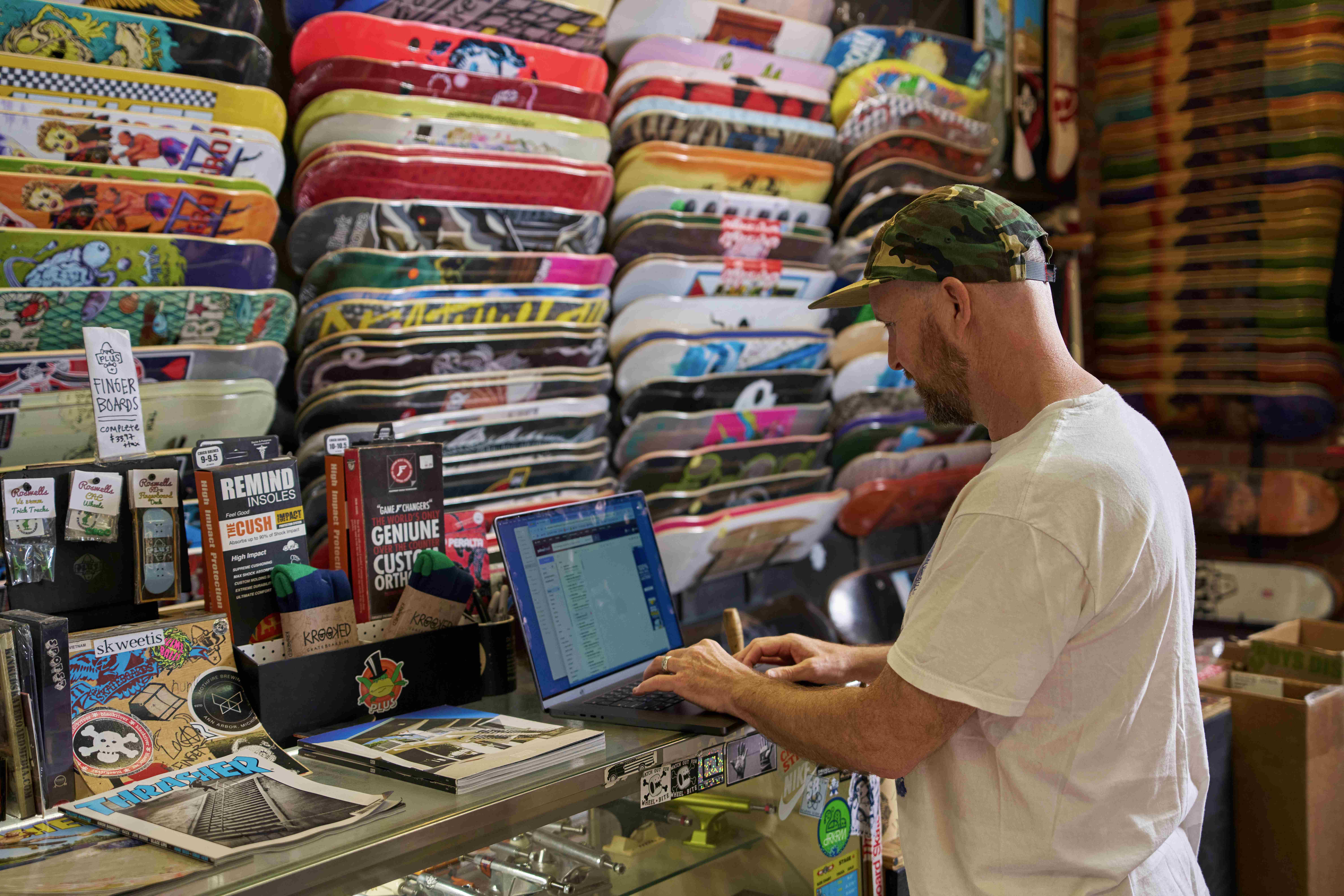 Small business owner uses laptop to run payroll from his retail shop. 