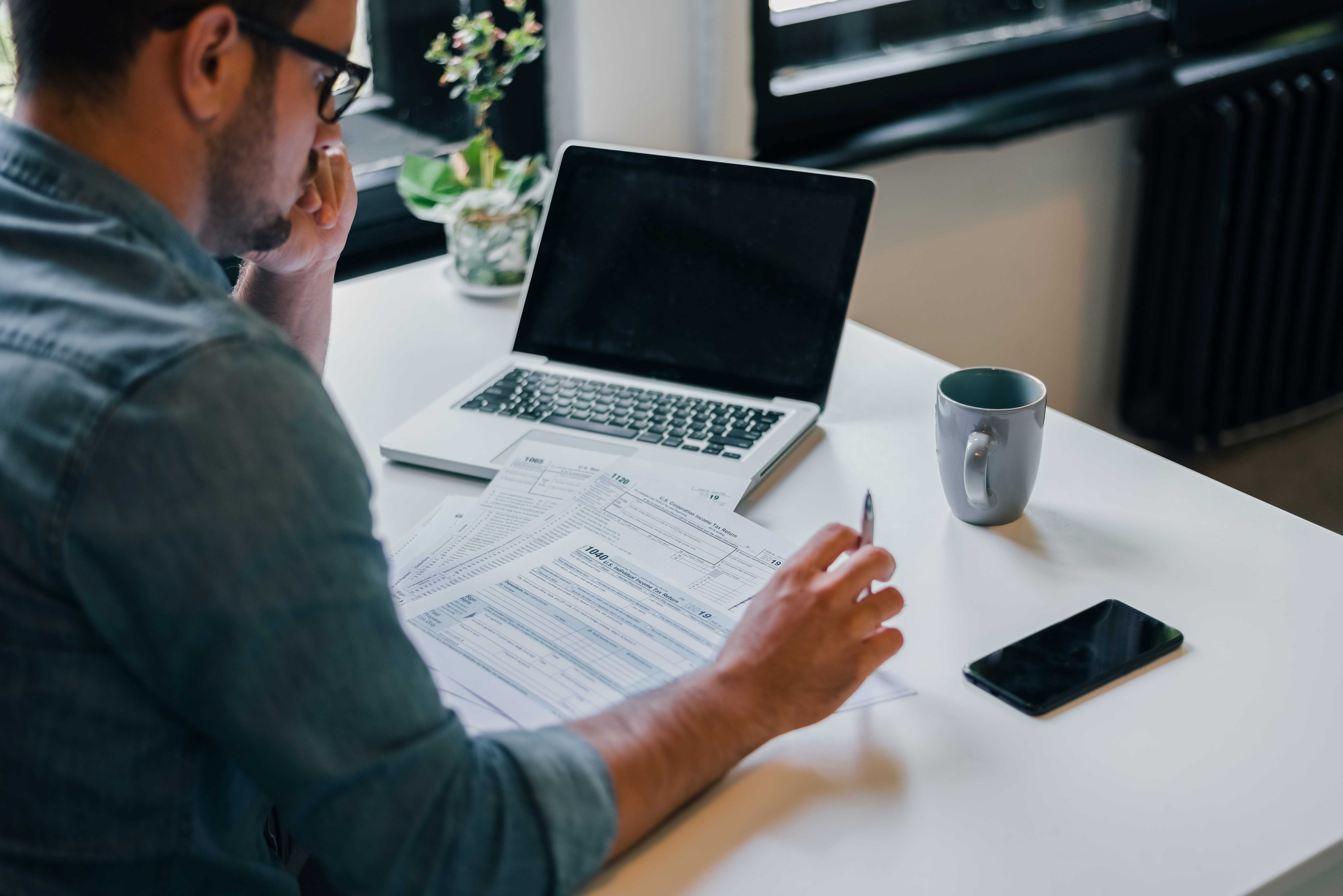 Entrepreneur in office reviewing income tax return documents for IRS to make tax season easier. 