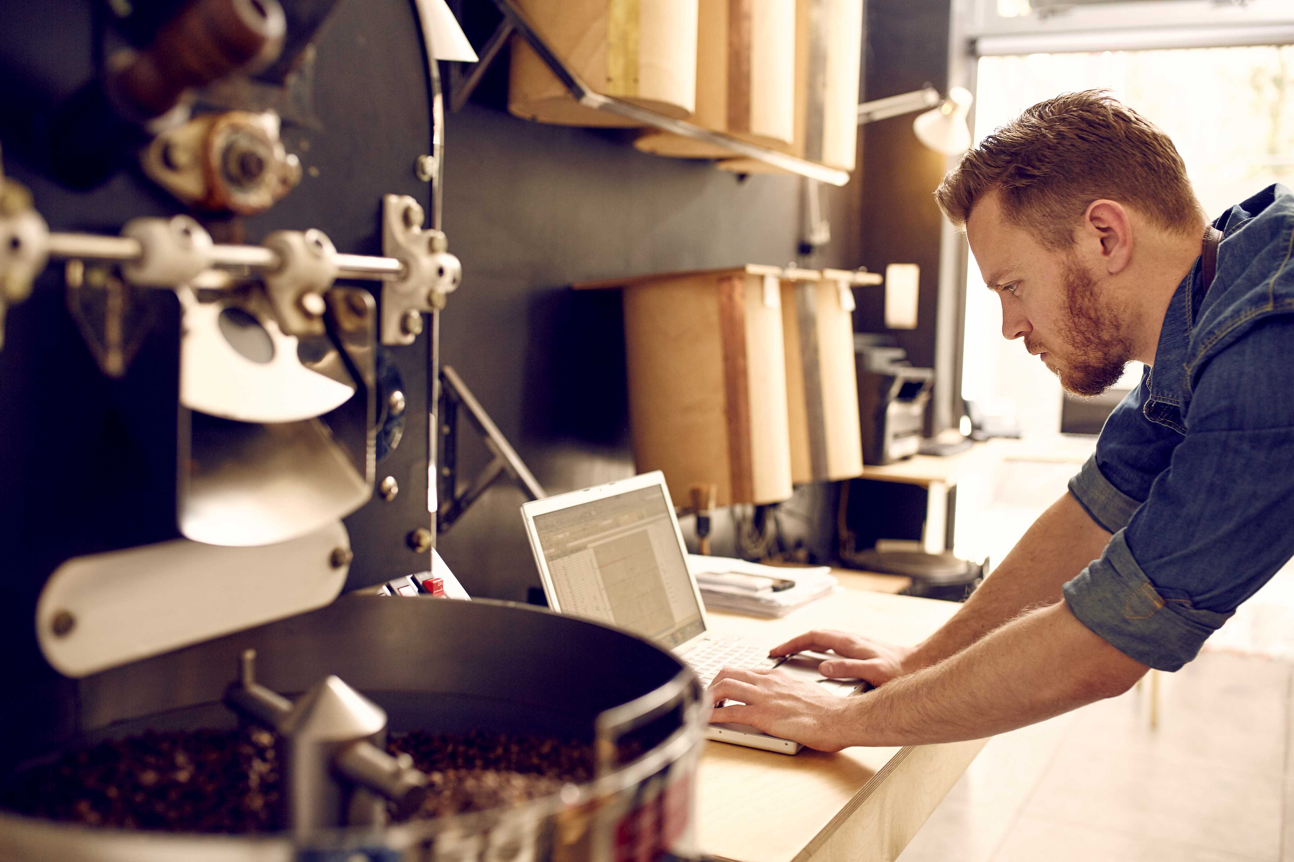 Small business owner of roastery checks payroll on laptop. 