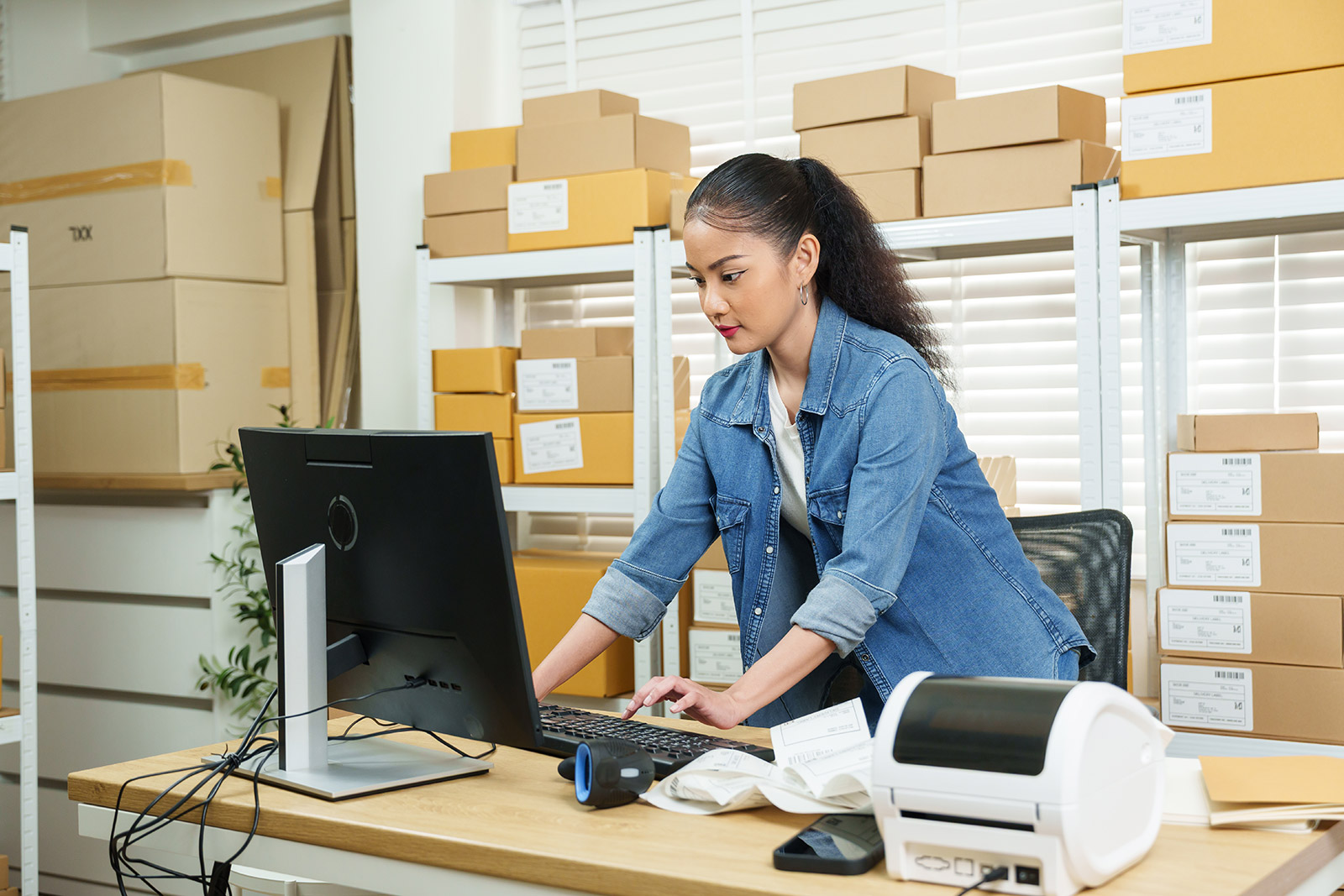 Woman small business owner doing income taxes at desktop computer in her store