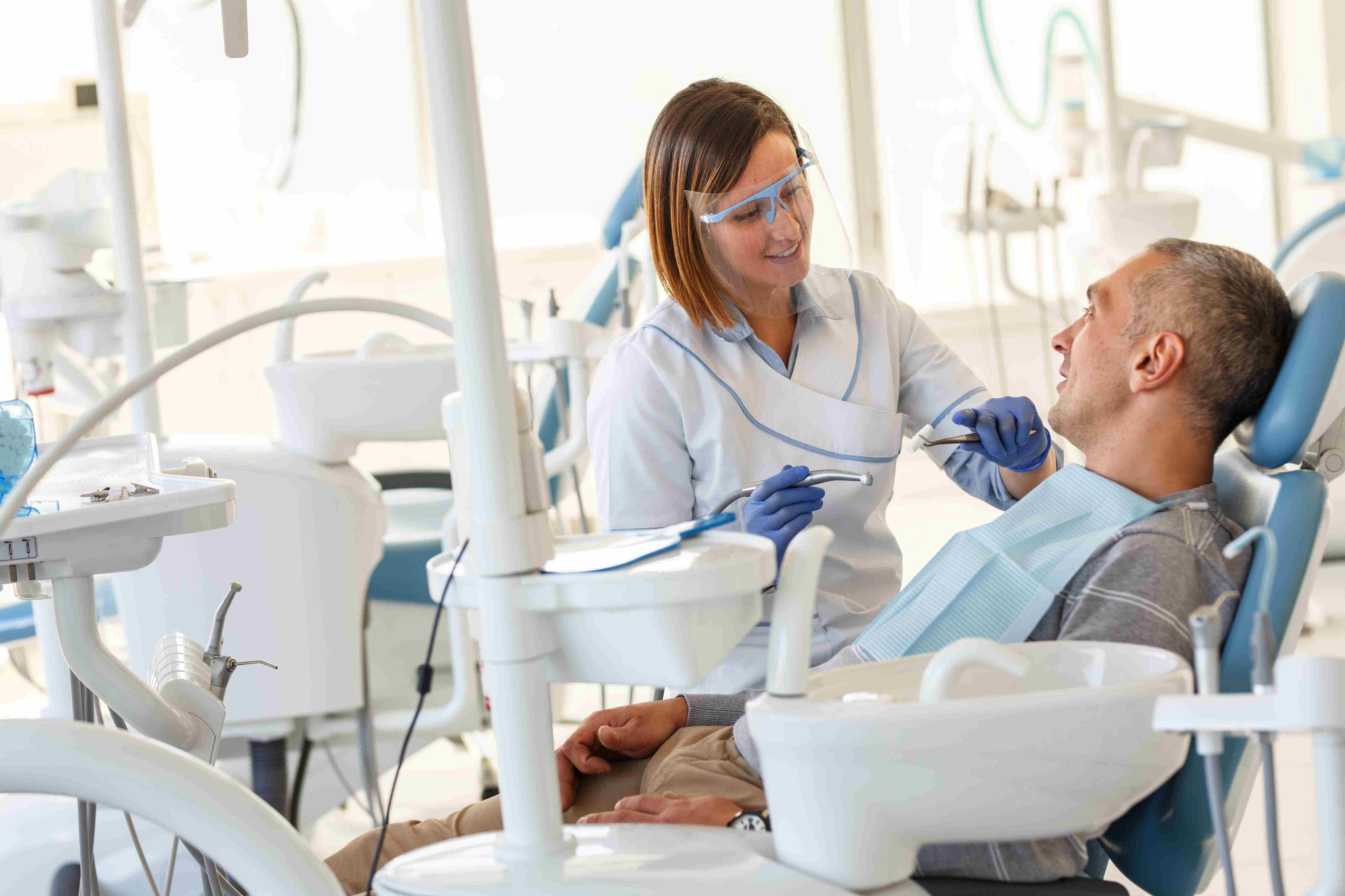 Dental hygienist talks with male patient in dental practice.