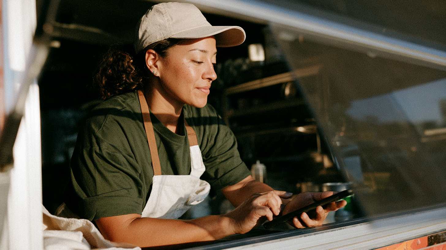 Female food truck owner uses mobile phone to set payroll schedule for staff
