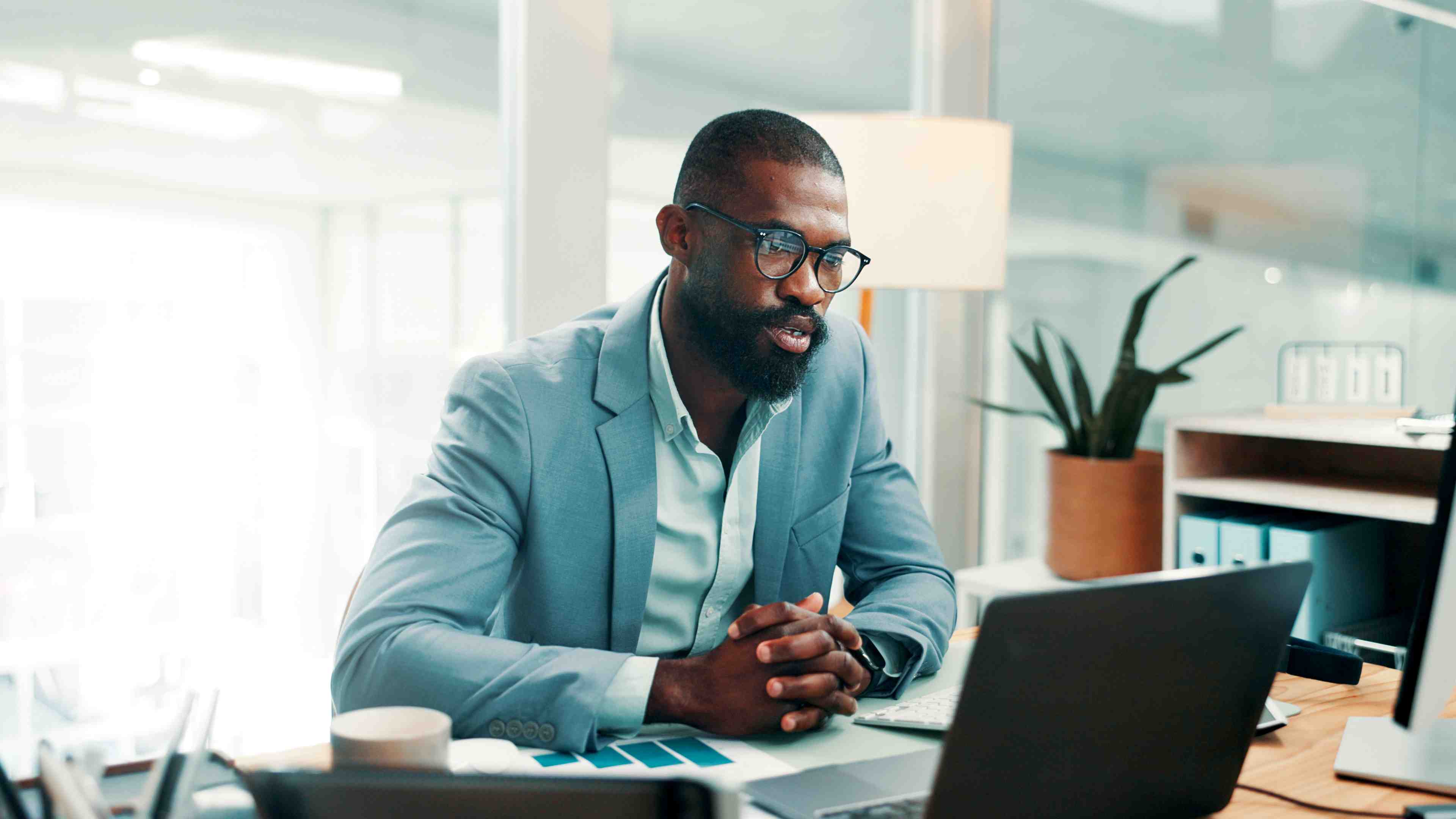Accountant sitting at desk reviews s-corp payroll software options on laptop.
