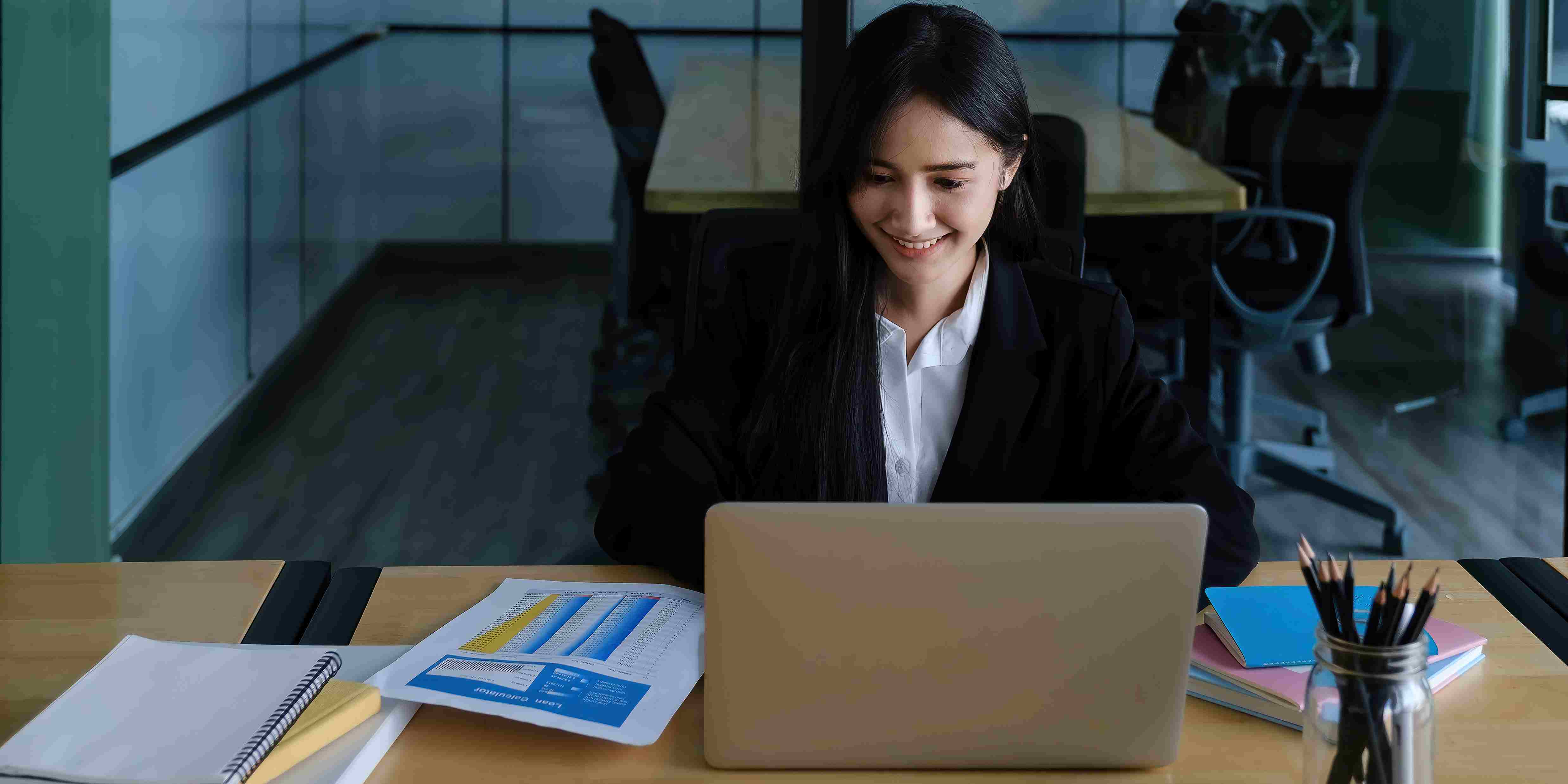 Accountant works at desk with laptop and paperwork.