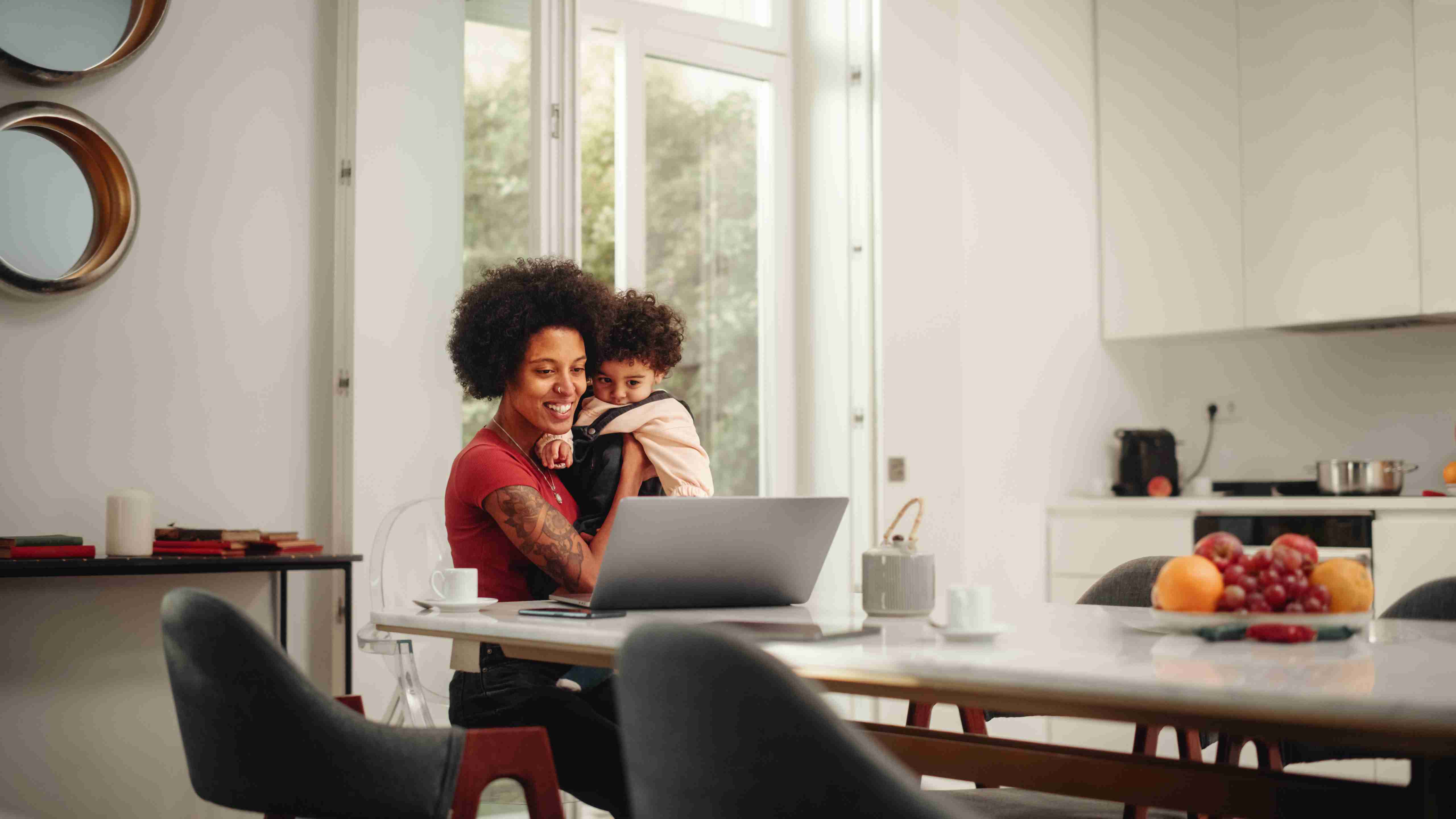 Mother and child at kitchen table working on laptop
